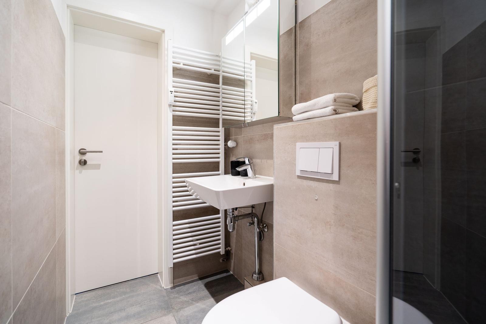Bathroom with sink, mirror, heater, and shower.