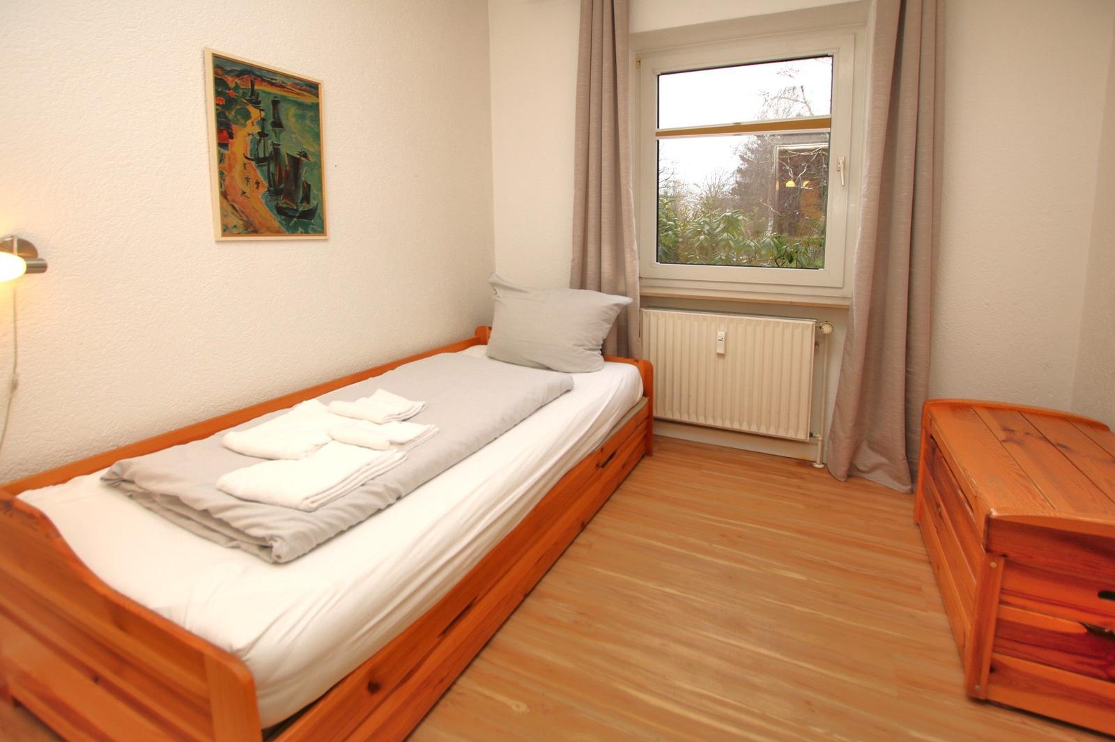 Ein Schlafzimmer mit einem Bett, einem Holzschrank und einem Fenster mit Blick auf die Umgebung.
