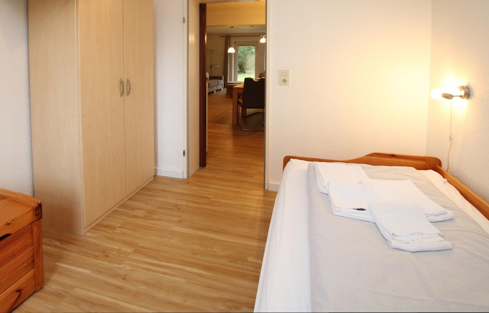 Schlafzimmer mit Bett, Kleiderschrank und Sicht in Wohnbereich.