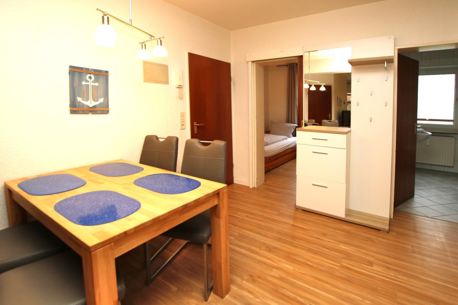 Essbereich mit Tisch und Stühlen, Blick in Schlafzimmer und Bad.