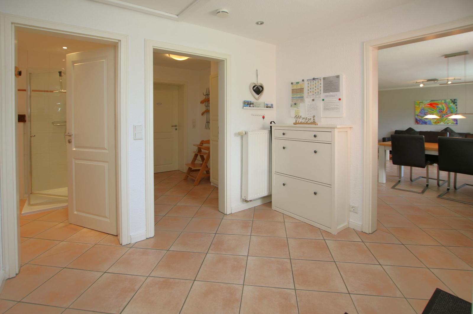 Haus mit Flur, Schlafzimmer und Bad. Fliesenboden und weiße Möbel.