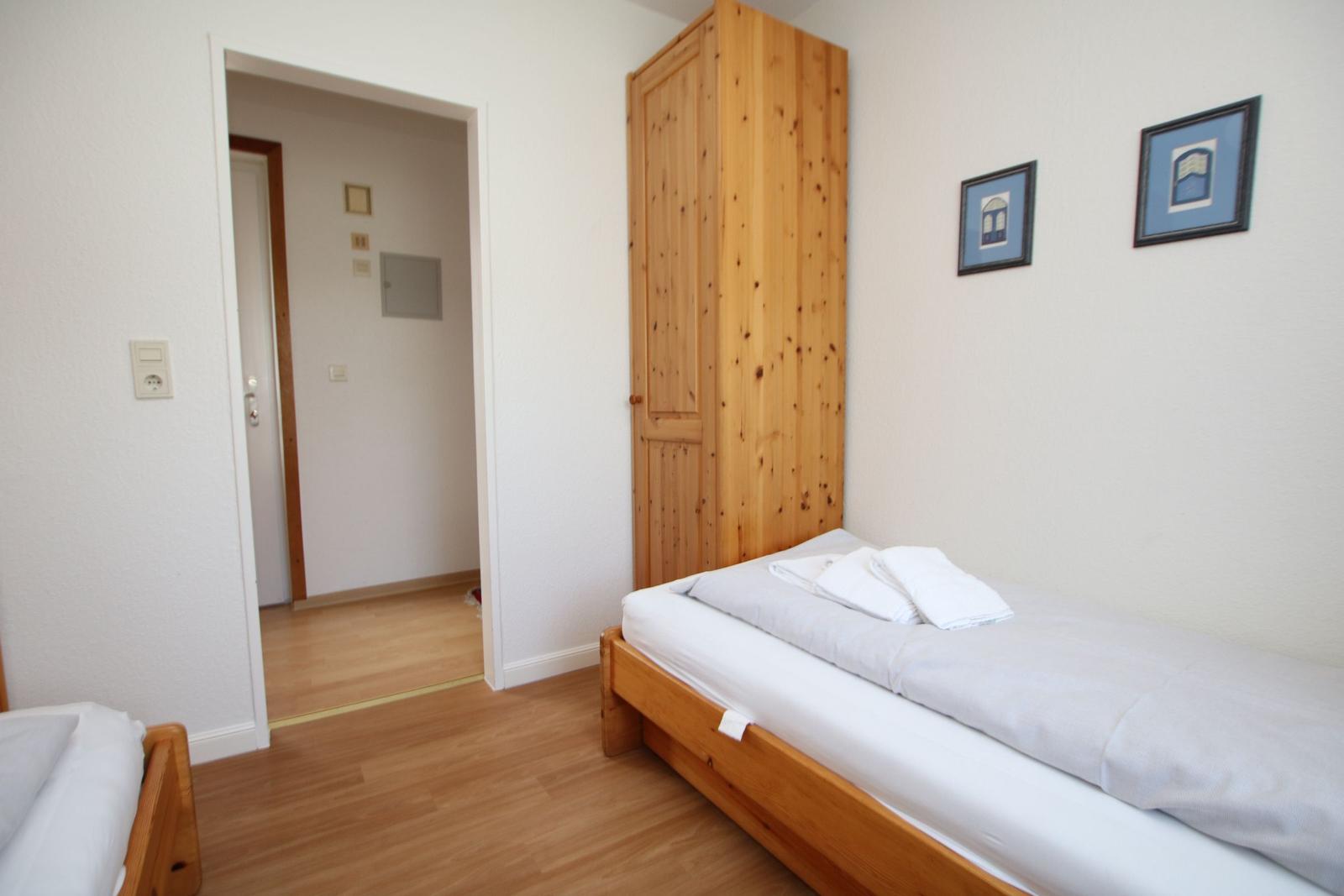 Ein Schlafzimmer mit Holzbett, Kleiderschrank und zwei Bildern an der Wand.