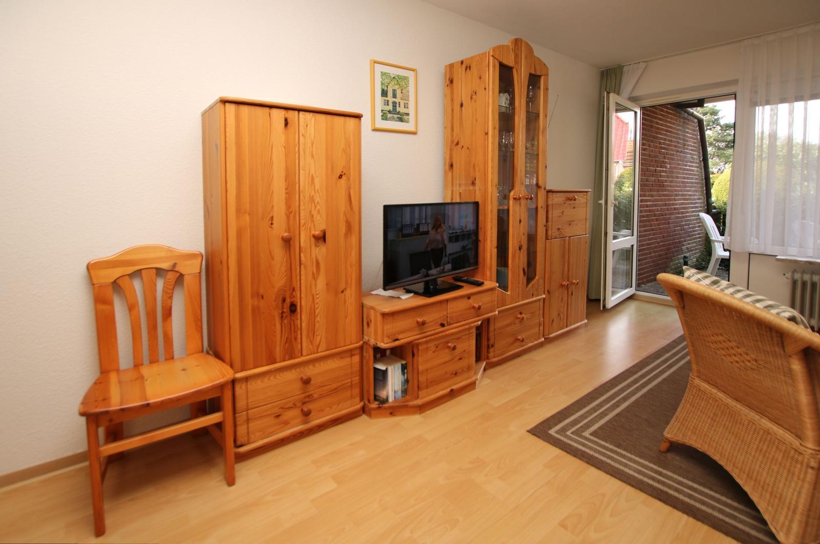 Wohnzimmer mit Holzmöbeln, Fernseher und Terrassentür.