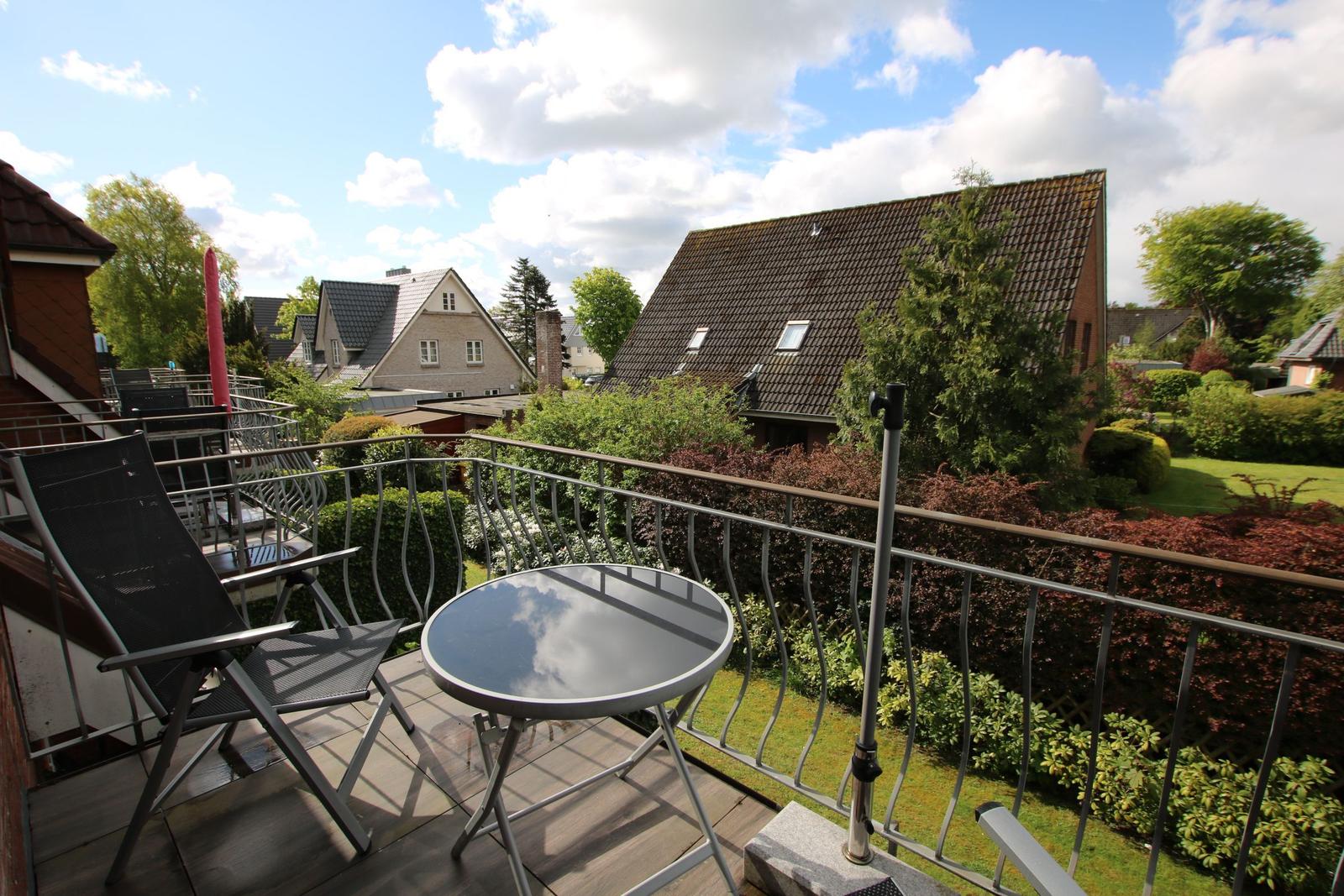 Terrace with table and chairs, view of gardens and neighboring houses.