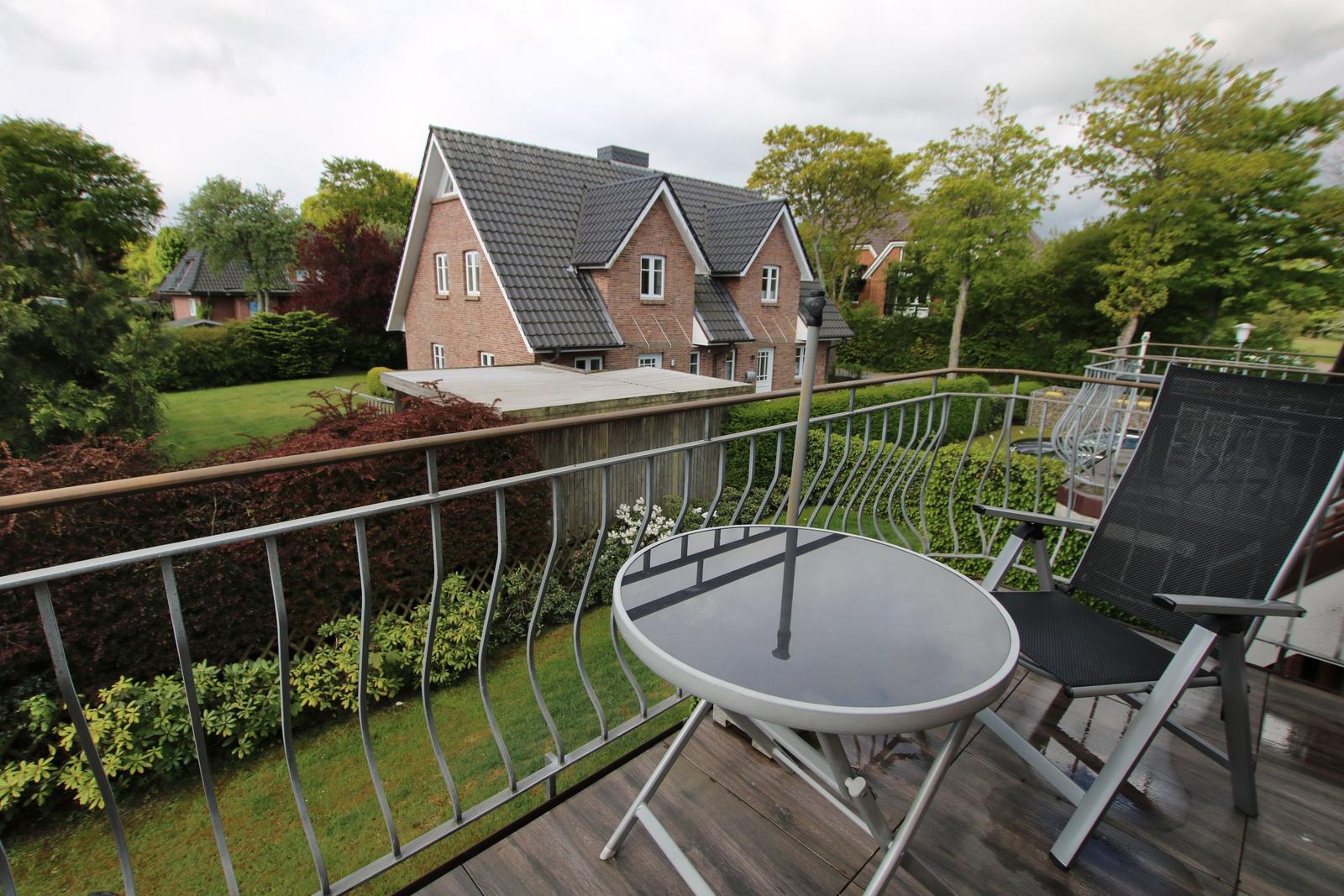 Terrace with table and chair, view of garden and house.