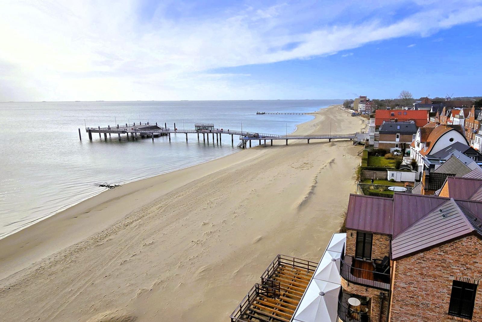 Strand mit Steg und Häusern am Wasser