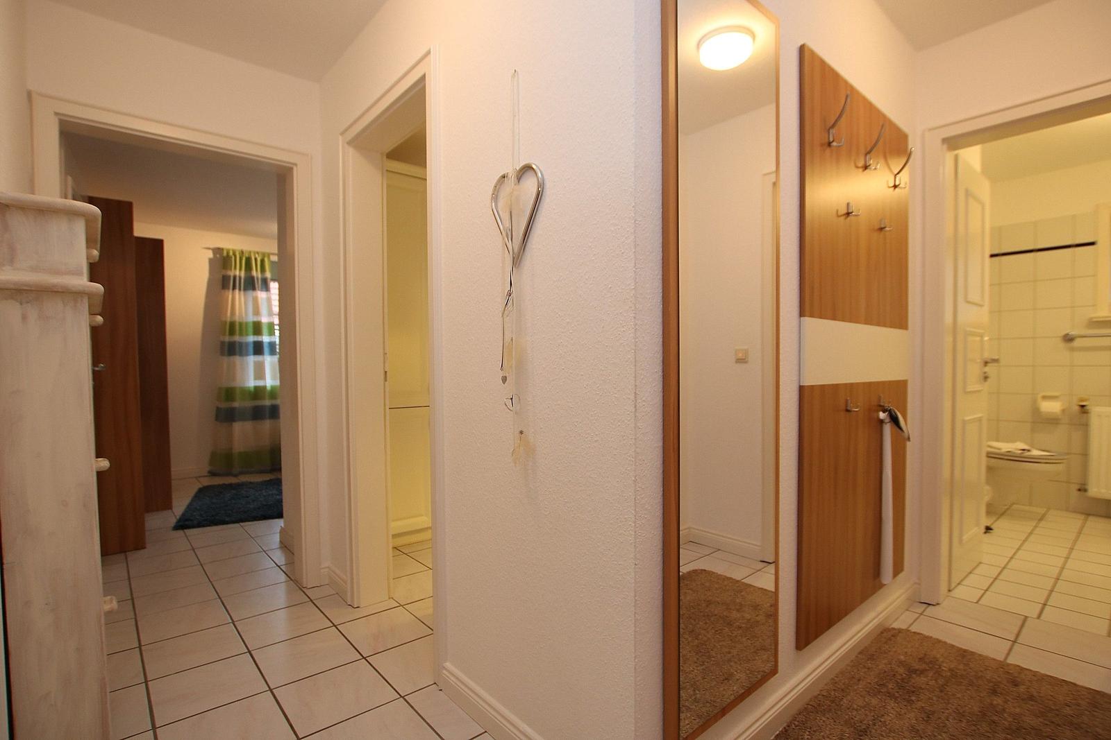 Flur mit Spiegel, Garderobe und Blick in Bad und Schlafzimmer