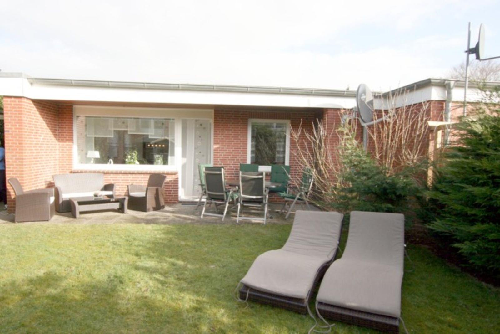 Hinterhof mit Garten, Liegen und Sitzgruppe vor dem Haus.