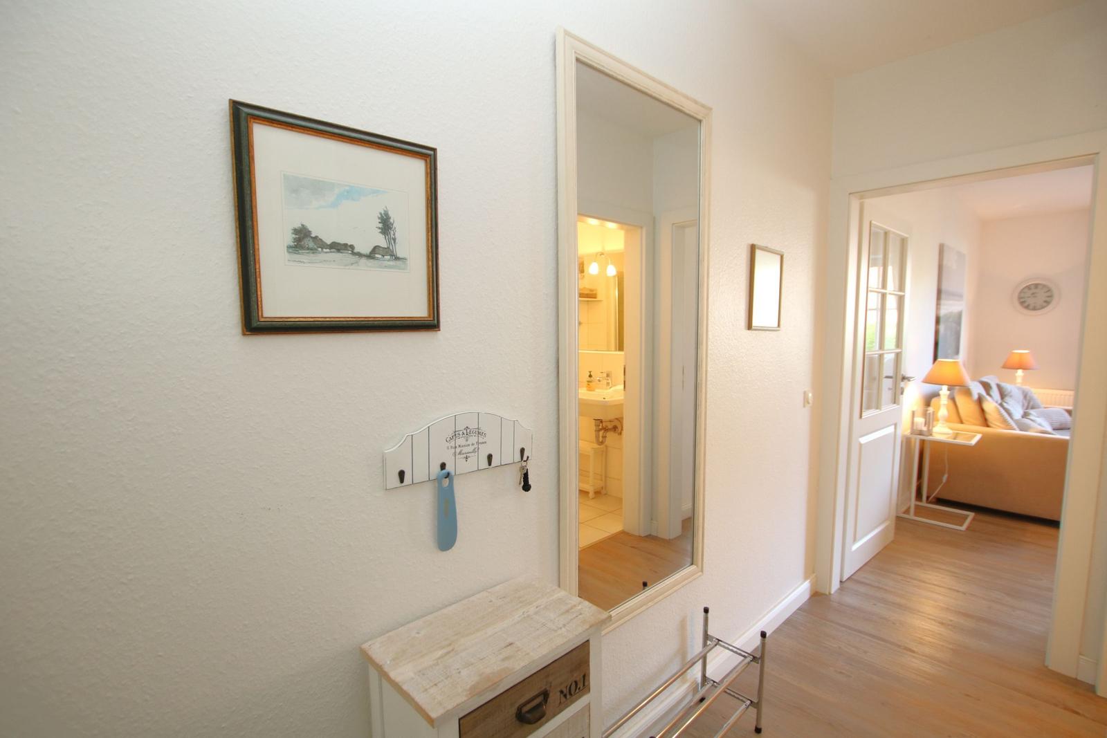 Flur mit Bild, Kleiderhaken und Blick in Bad und Wohnzimmer.