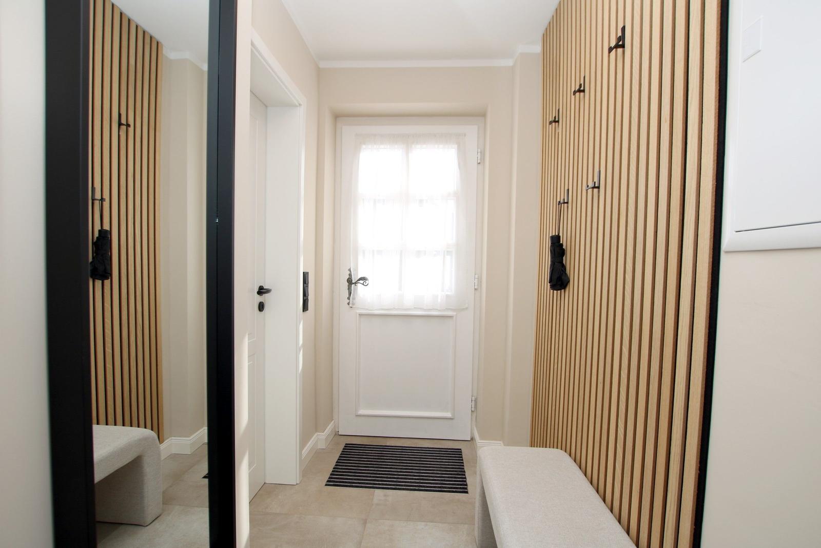 Eingangsbereich mit Holzwand, Bänken und Haken für Regenbekleidung.