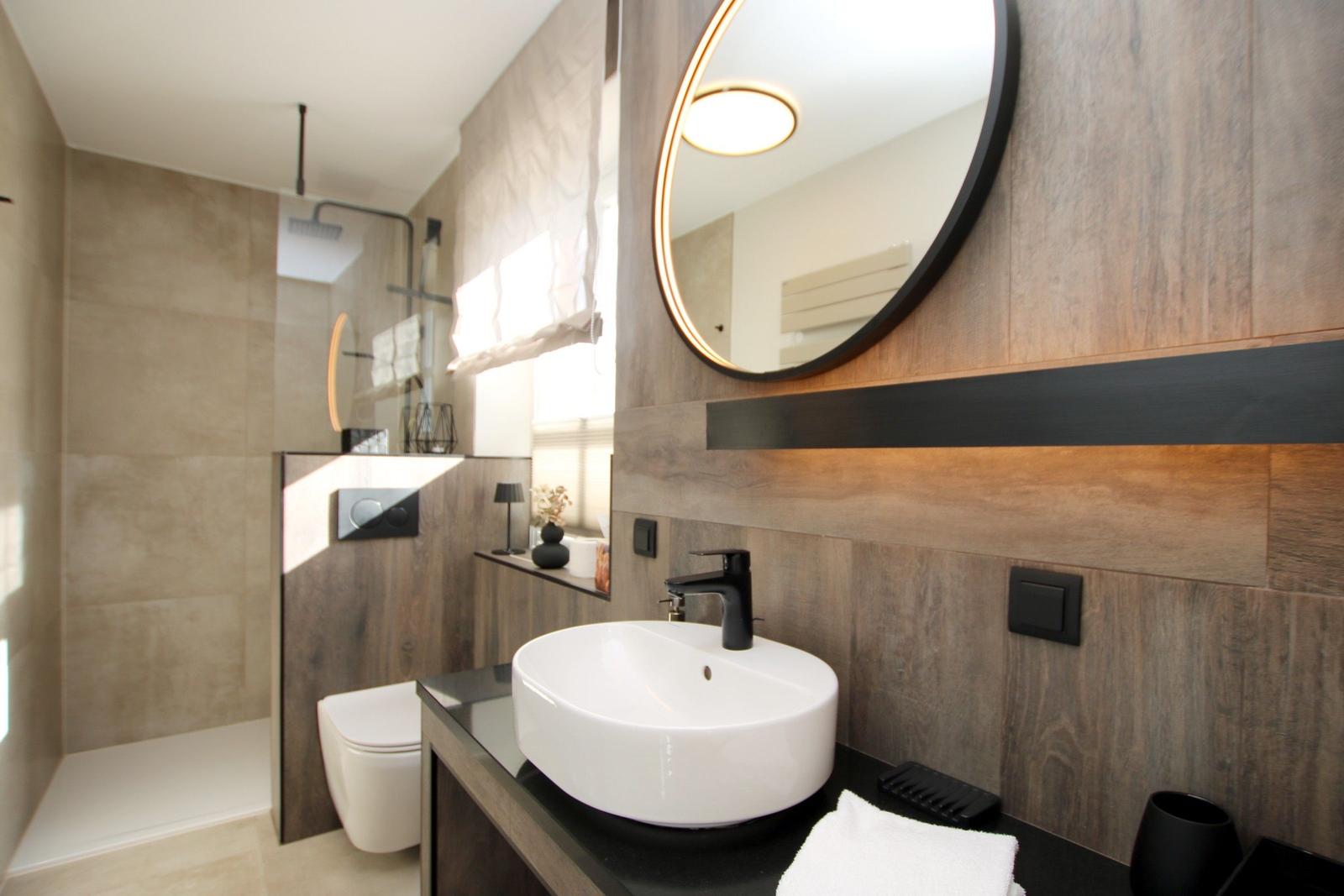 Badezimmer mit Waschbecken, Spiegel und Dusche.