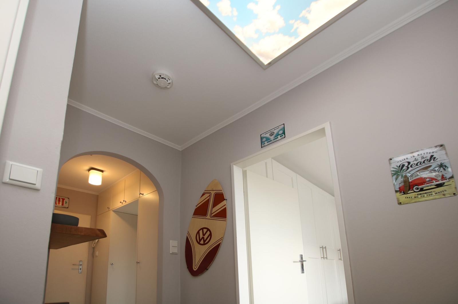 Flur mit Dachfenster, Wanddekoration und Tür zu einem Zimmer.