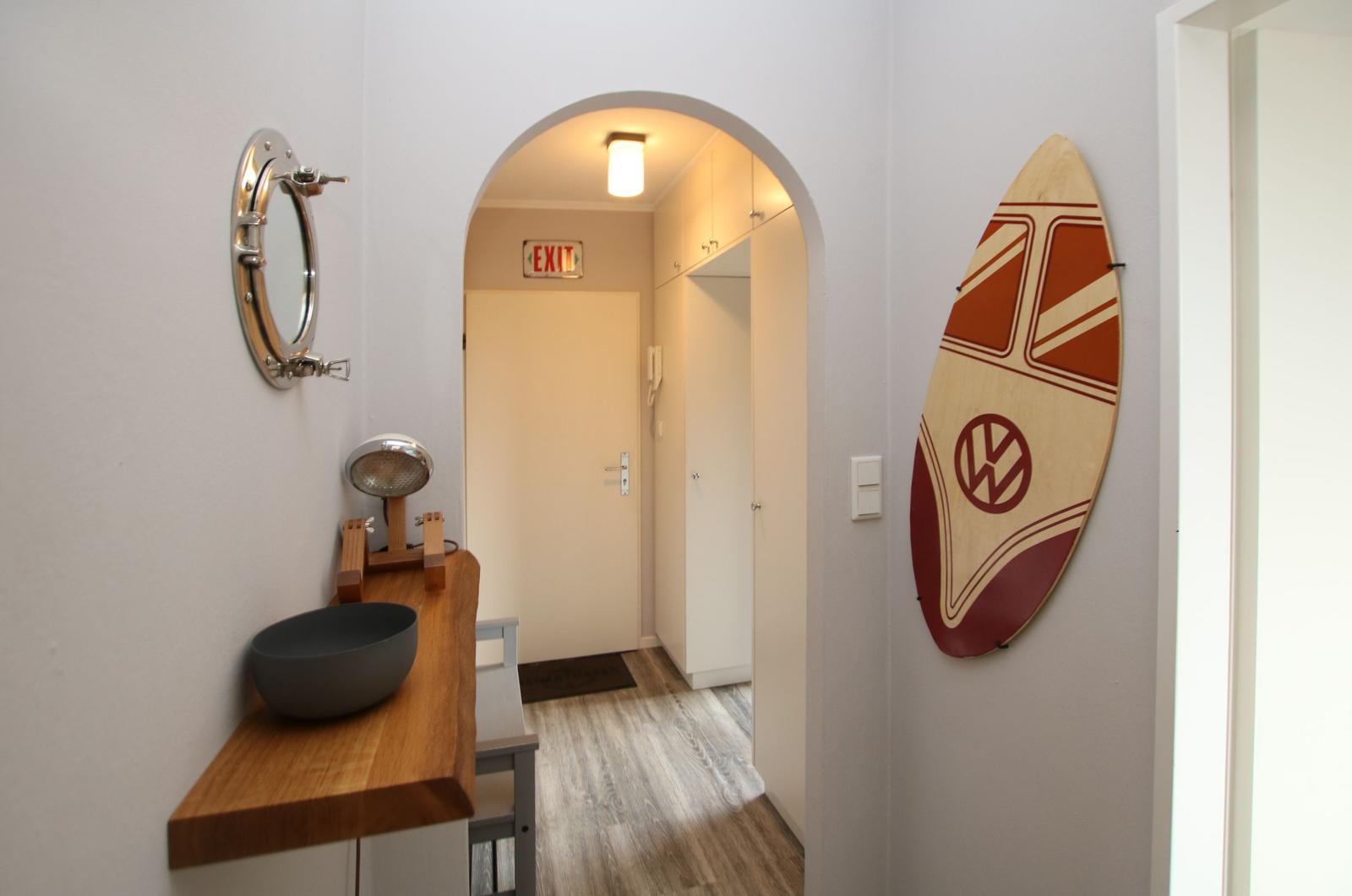 Hausflur mit Badezimmerbereich und VW-Surfbrett an der Wand.