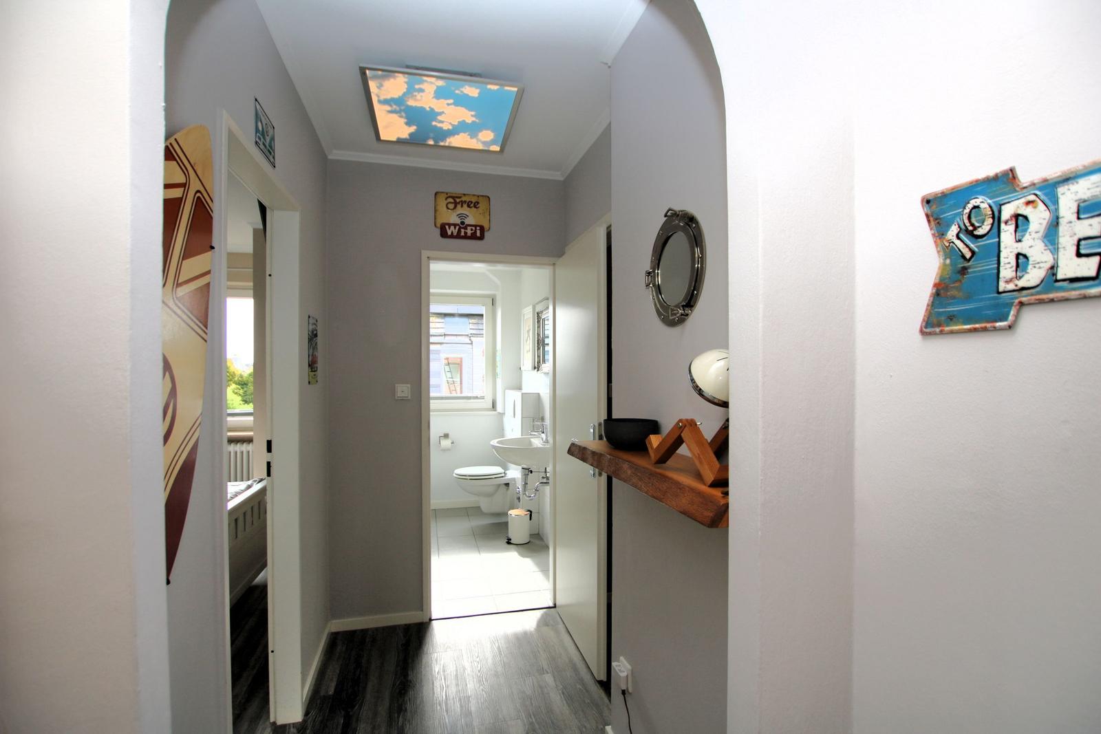Flur mit Blick in Bad und Schlafzimmer, Deckenlicht, Wanddekoration und Waschbecken