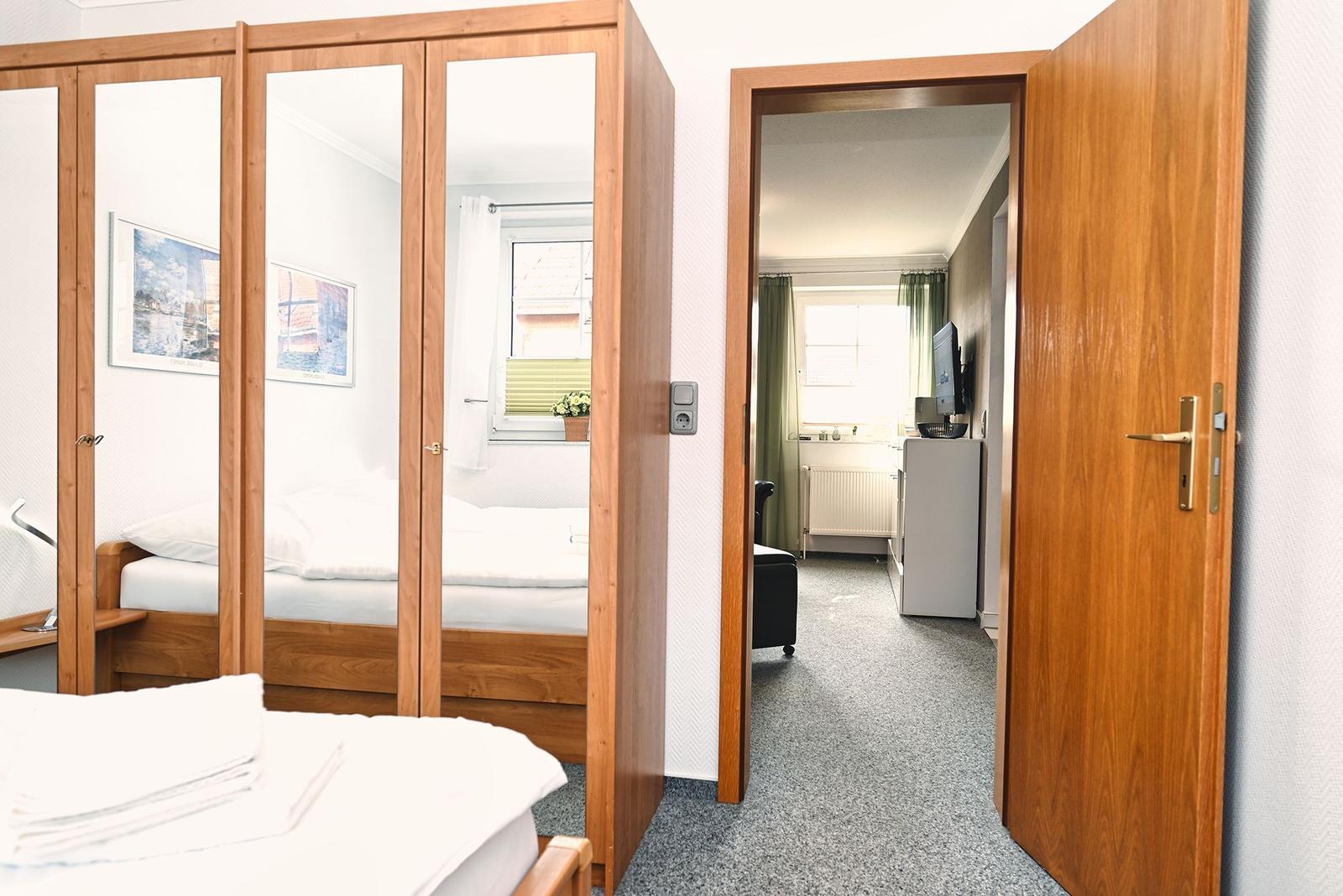 Schlafzimmer mit Spiegelschrank und Blick in die Küche.