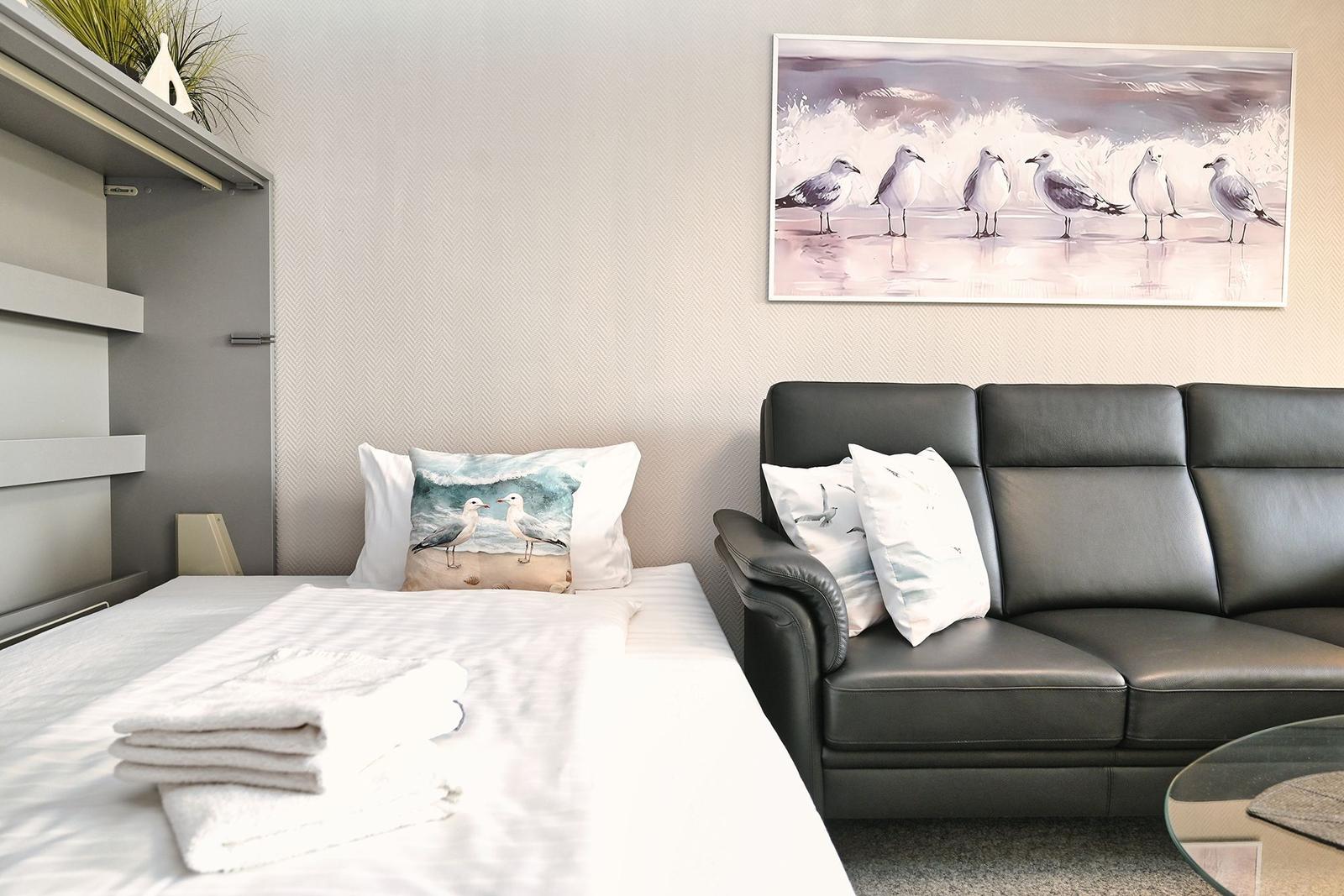 Schlafzimmer mit Bett, Sofa und Wandbild mit Möwen