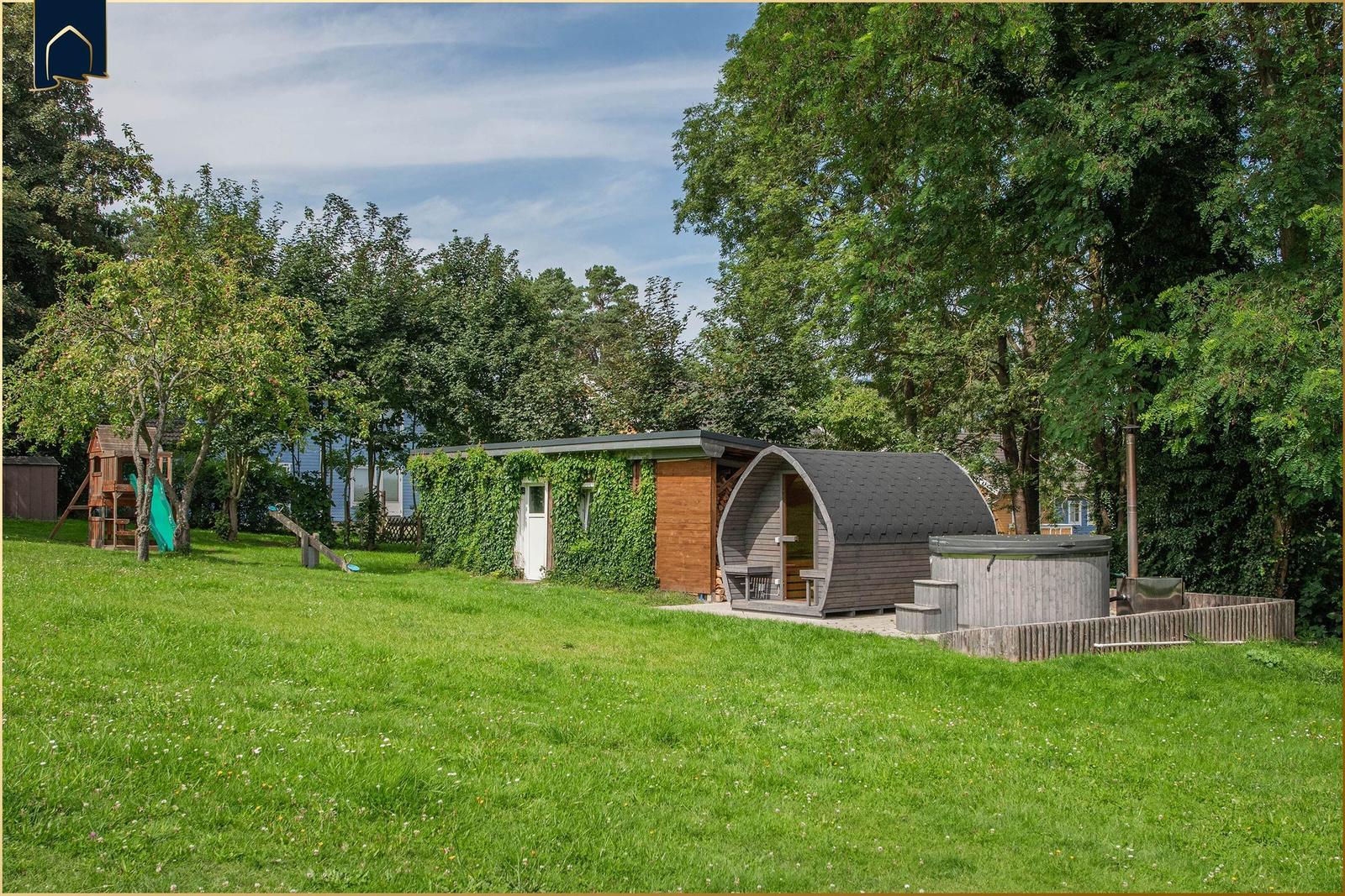 Haus mit Sauna, Whirlpool und Spielplatz auf grünem Grundstück.