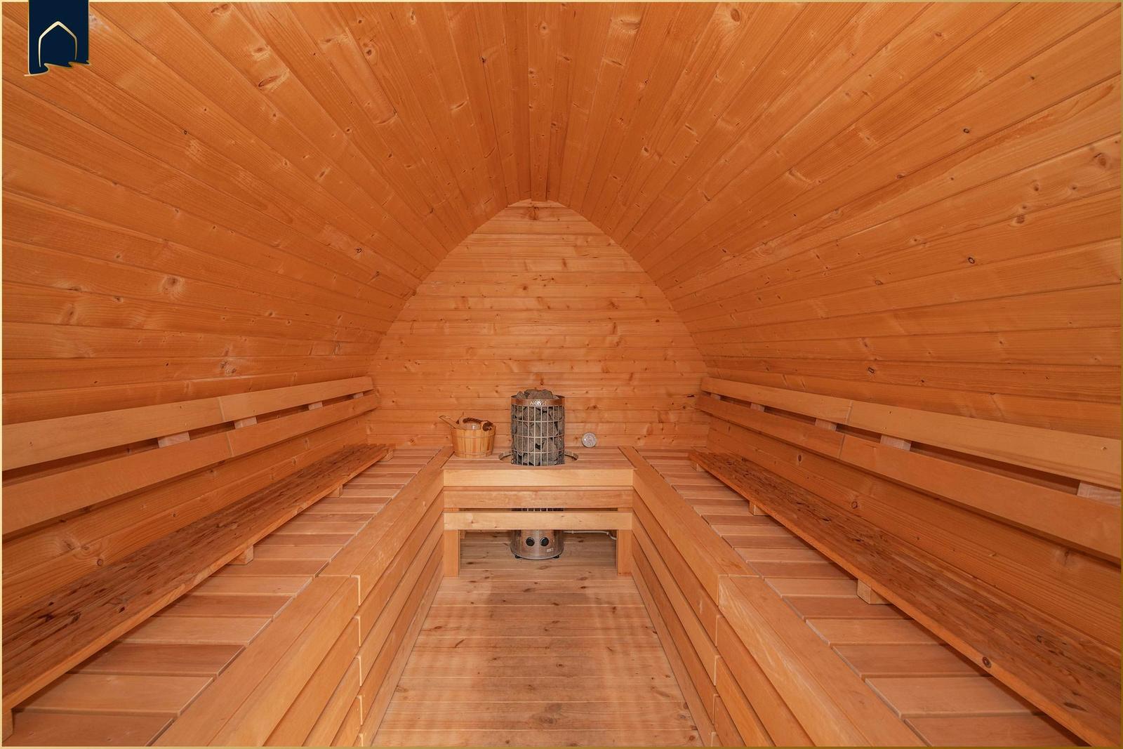 Holzsauna mit Sitzbänken und Heizung im Zentrum.