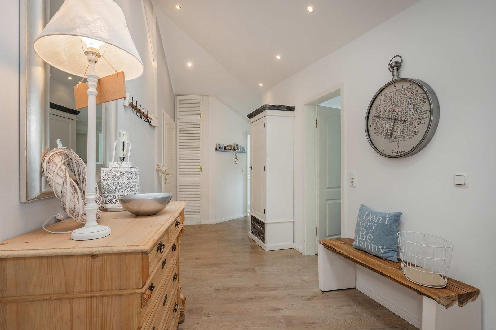 Hallenraum mit Holzboden, Kleiderschrank und Sitzbank mit Kissen.