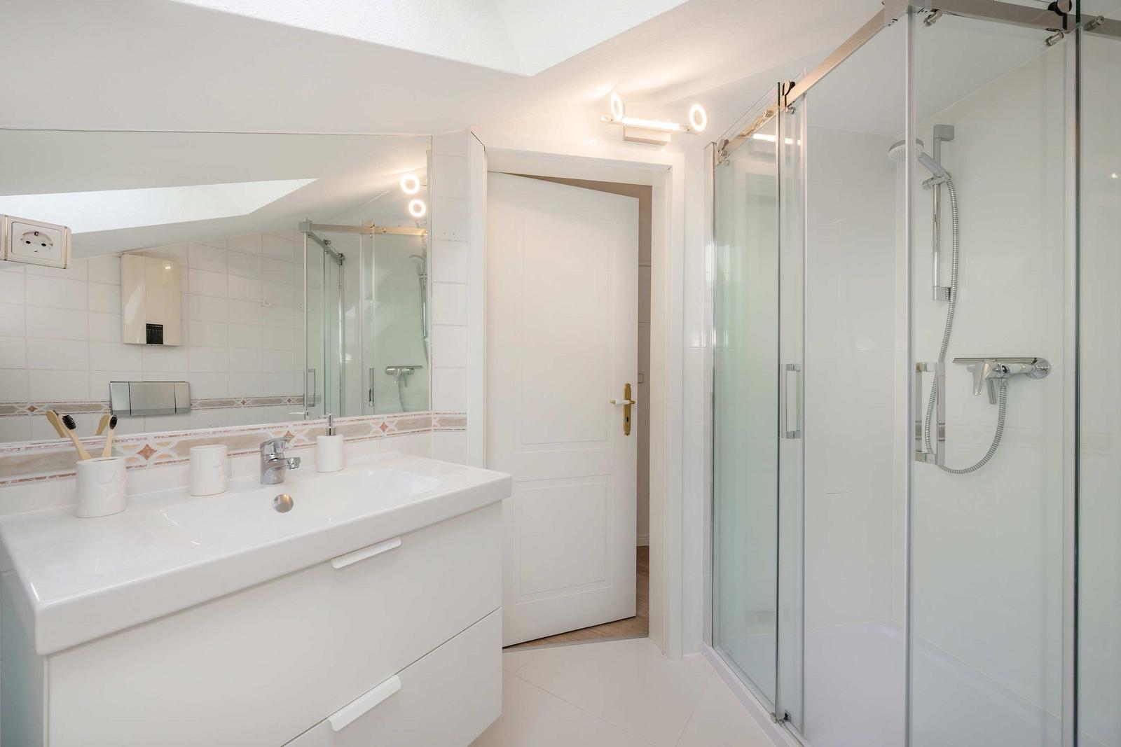 Badezimmer mit Dusche, Waschbecken und Spiegel
