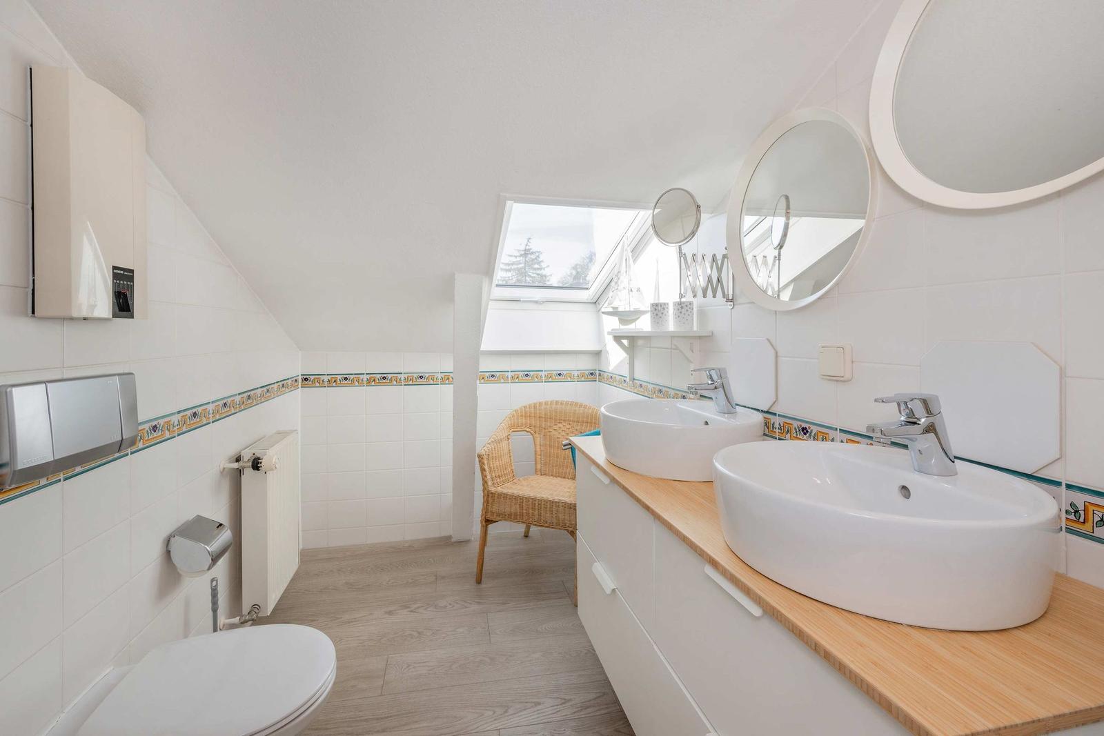 Badezimmer mit zwei Waschbecken, Duschbereich und Fenster
