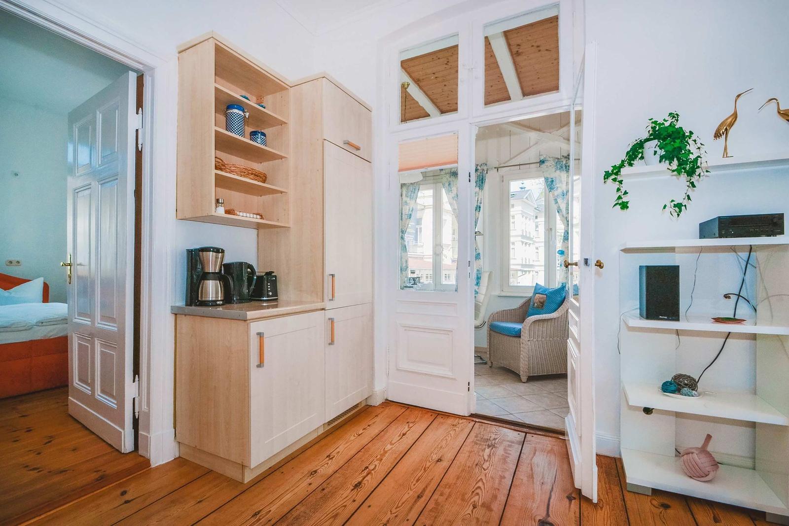 Kitchen with wooden floor, open shelves, and view into living and sleeping rooms.