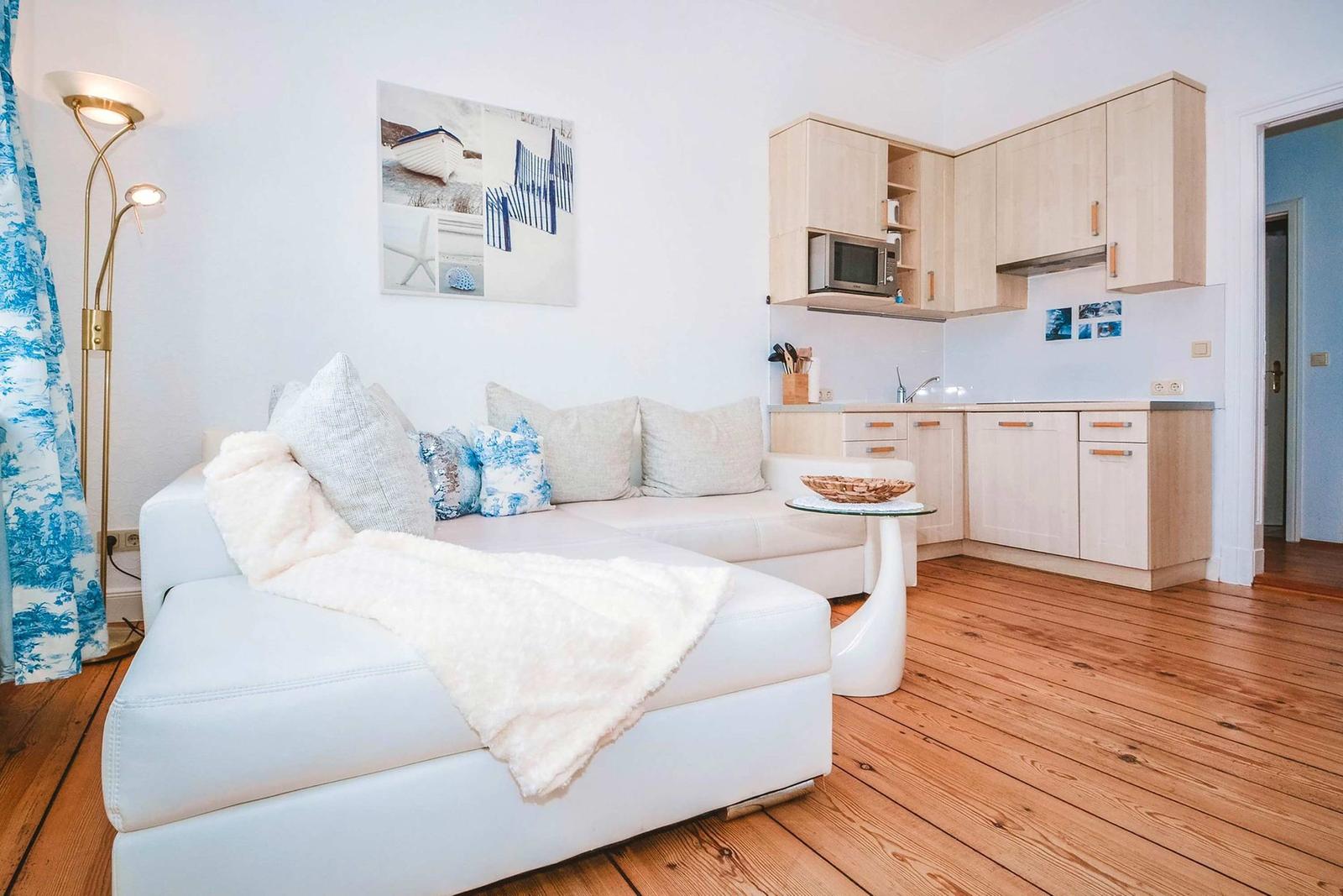Living room with sofa, kitchenette, and wooden floor.