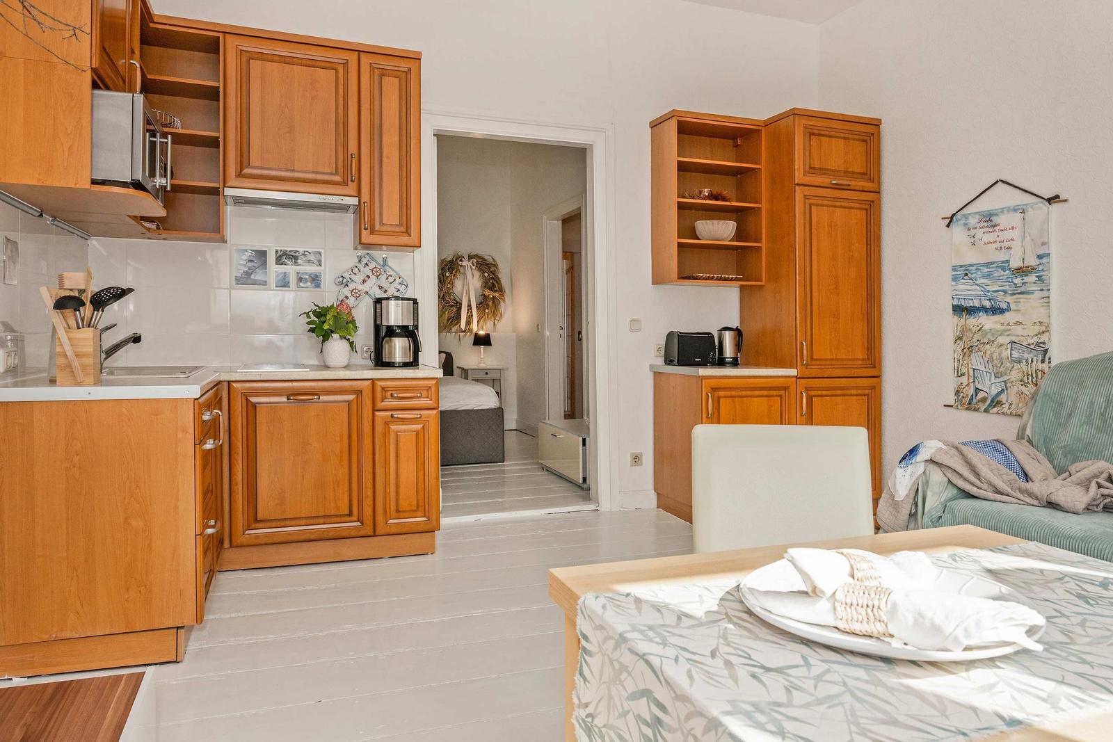 Küche mit Holzschränken, Esstisch und Blick in Schlafzimmer