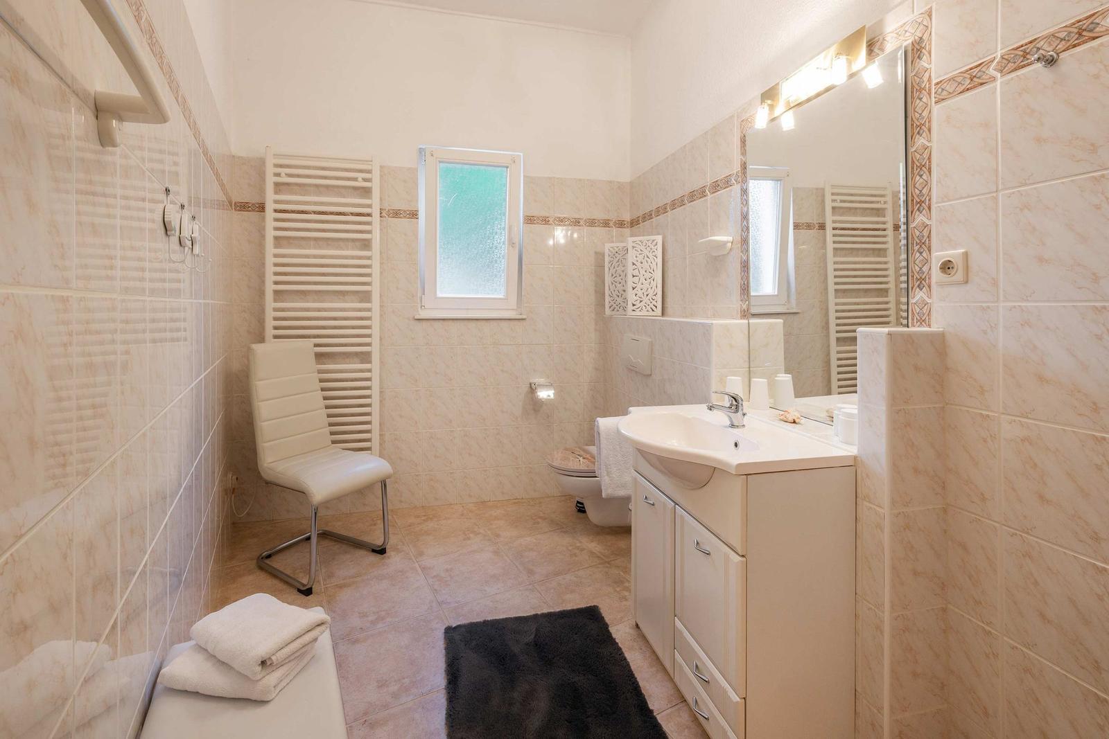 Badezimmer mit Waschbecken, Toilette, Badewanne und Fenster.