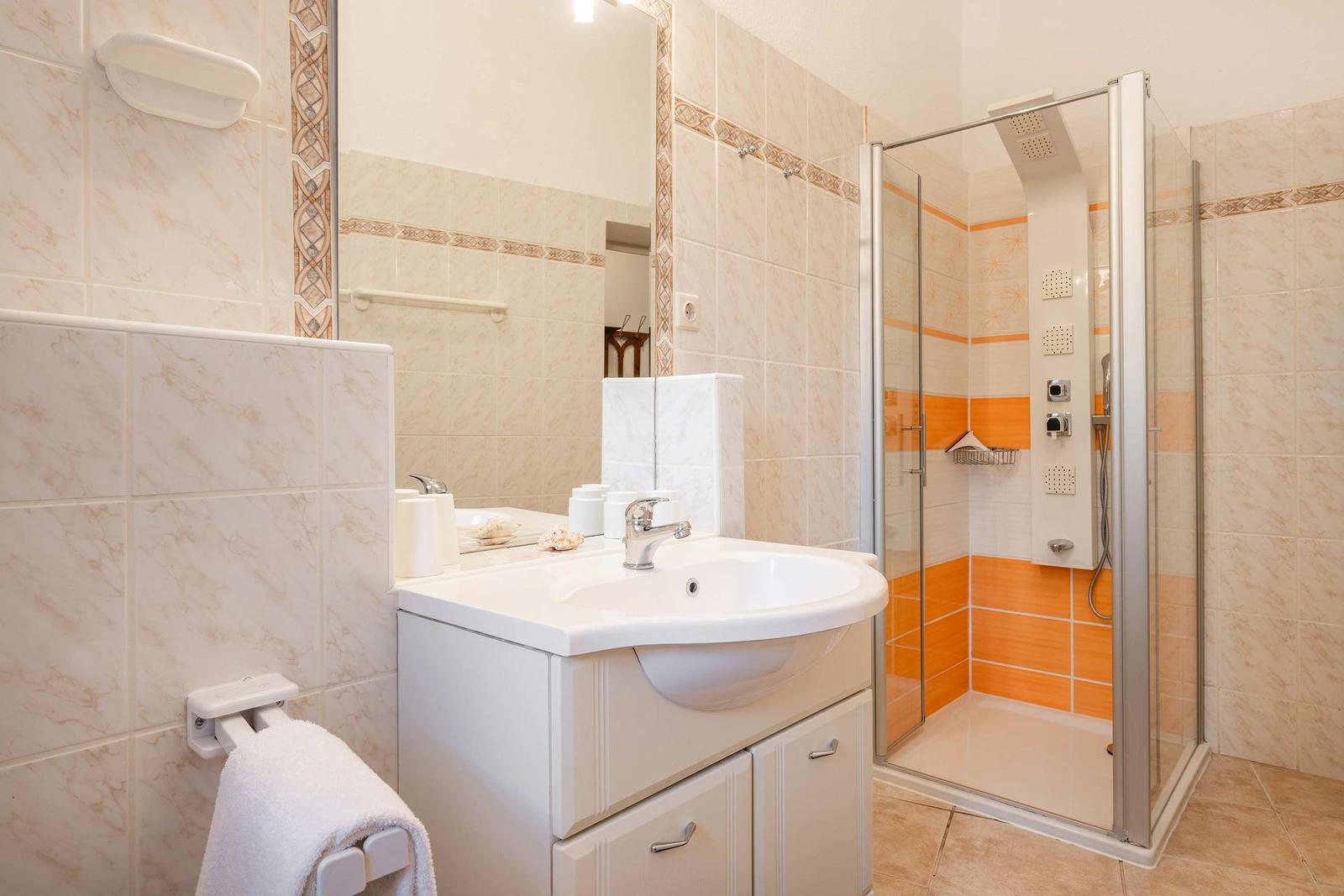Badezimmer mit Dusche, Waschbecken und Spiegel