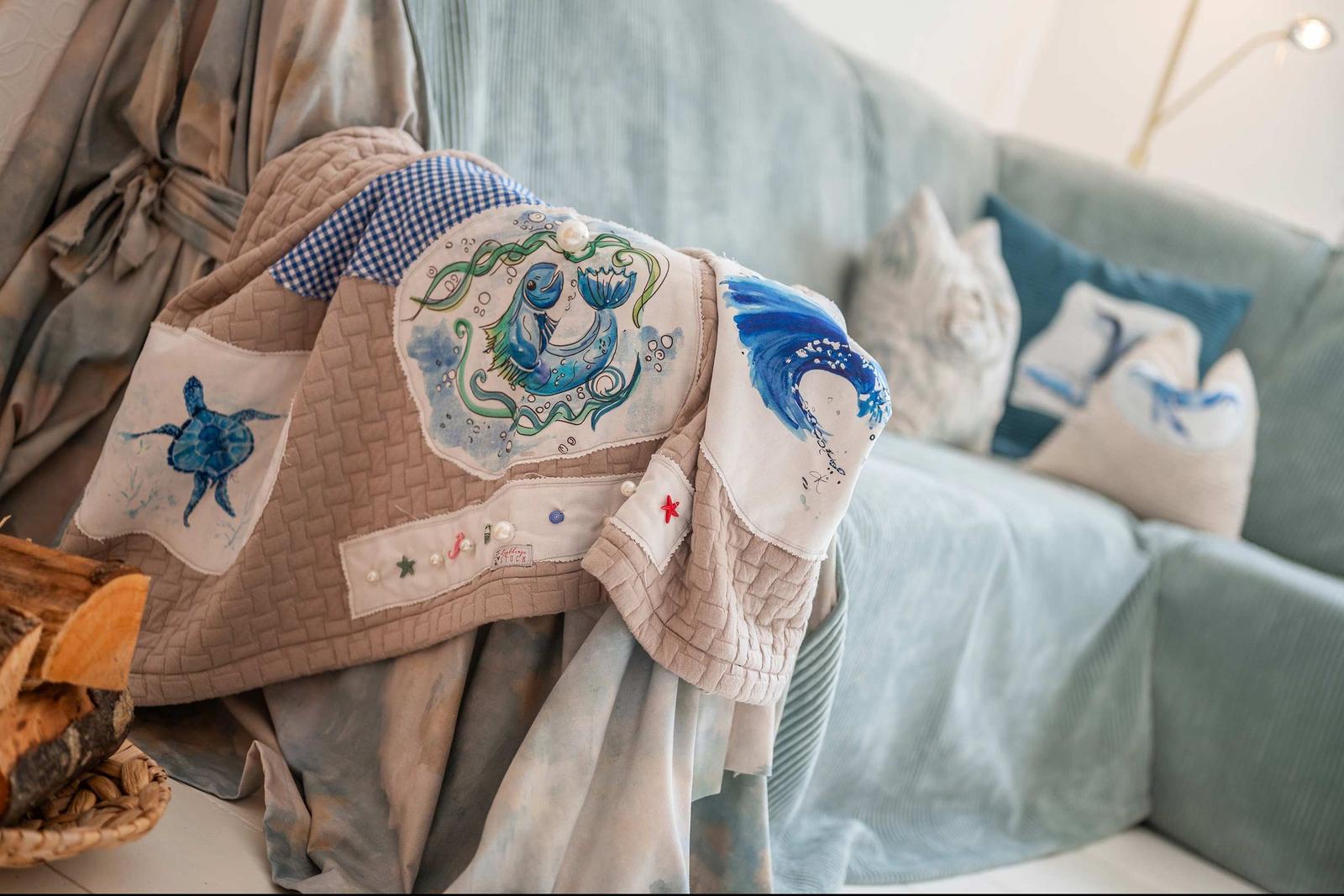 Ein Sofa mit Kissen und einer gestickten Decke mit Meerestiermotiven.