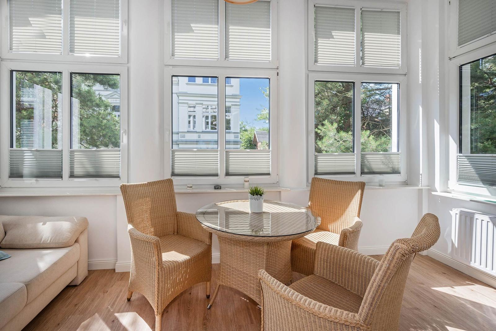 A room with four chairs around a round table and large windows with a view outside.