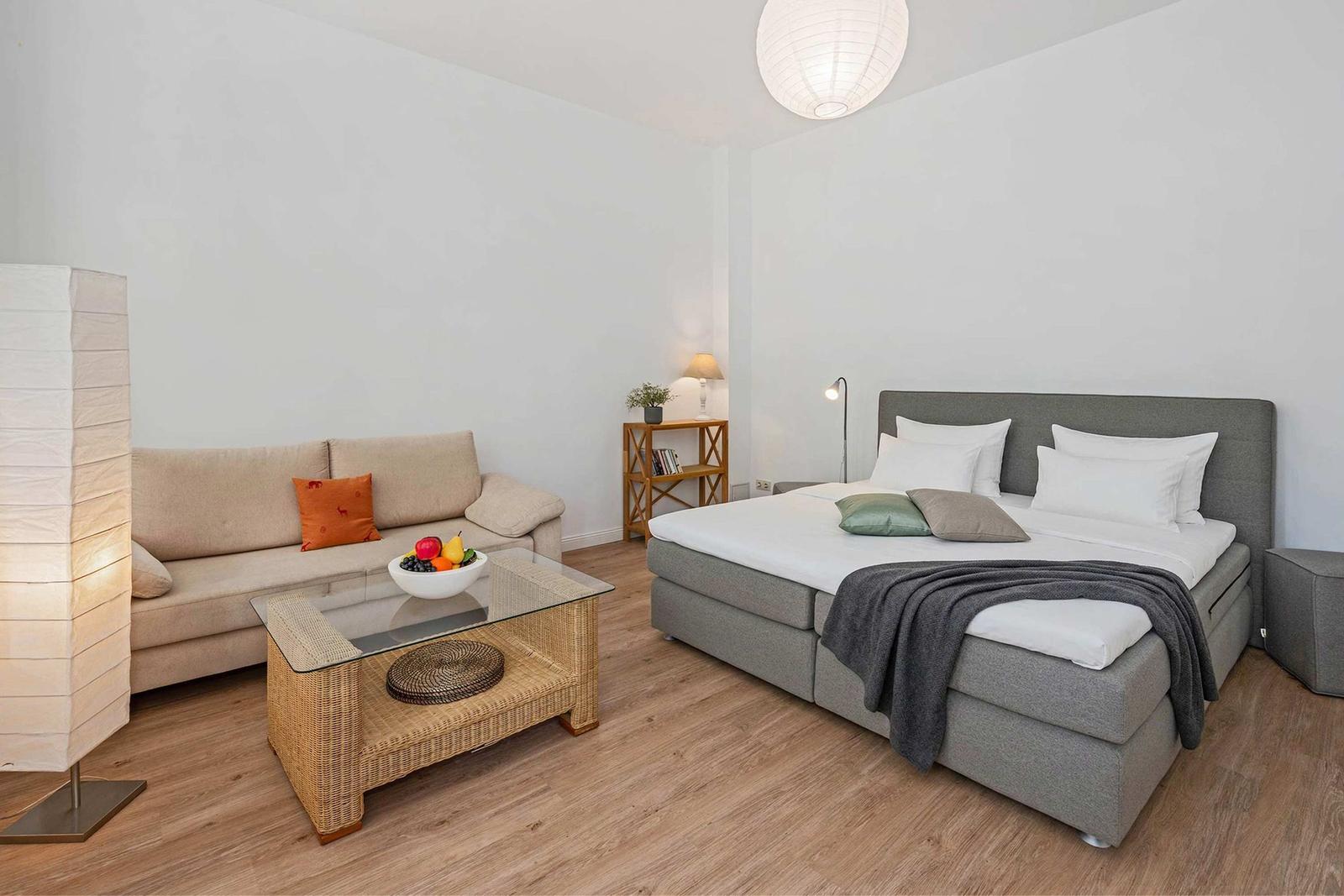 A bedroom with a bed, a sofa, and a table.
