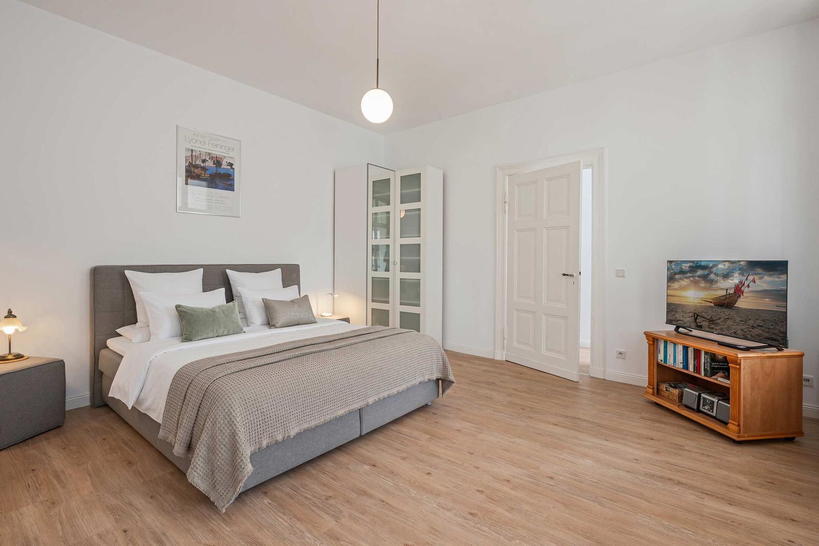 Bedroom with bed, TV stand and glass wall