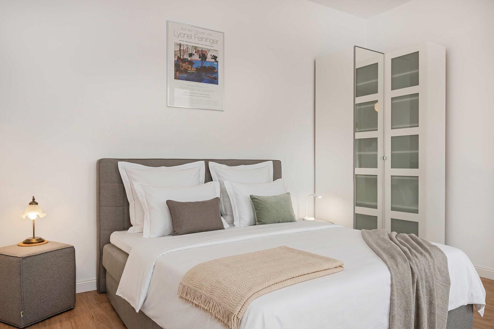 Bedroom with bed, nightstand, and wardrobe. Wall art and ceiling lighting.