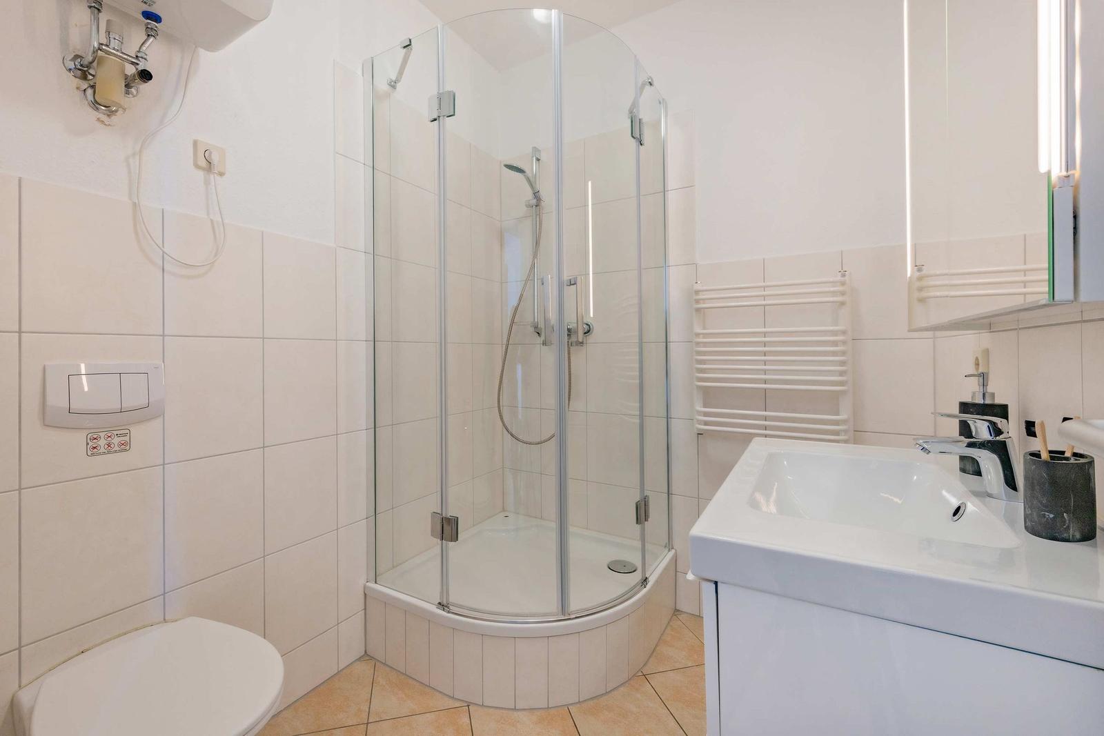 Badezimmer mit Dusche, Waschbecken und Toilette.