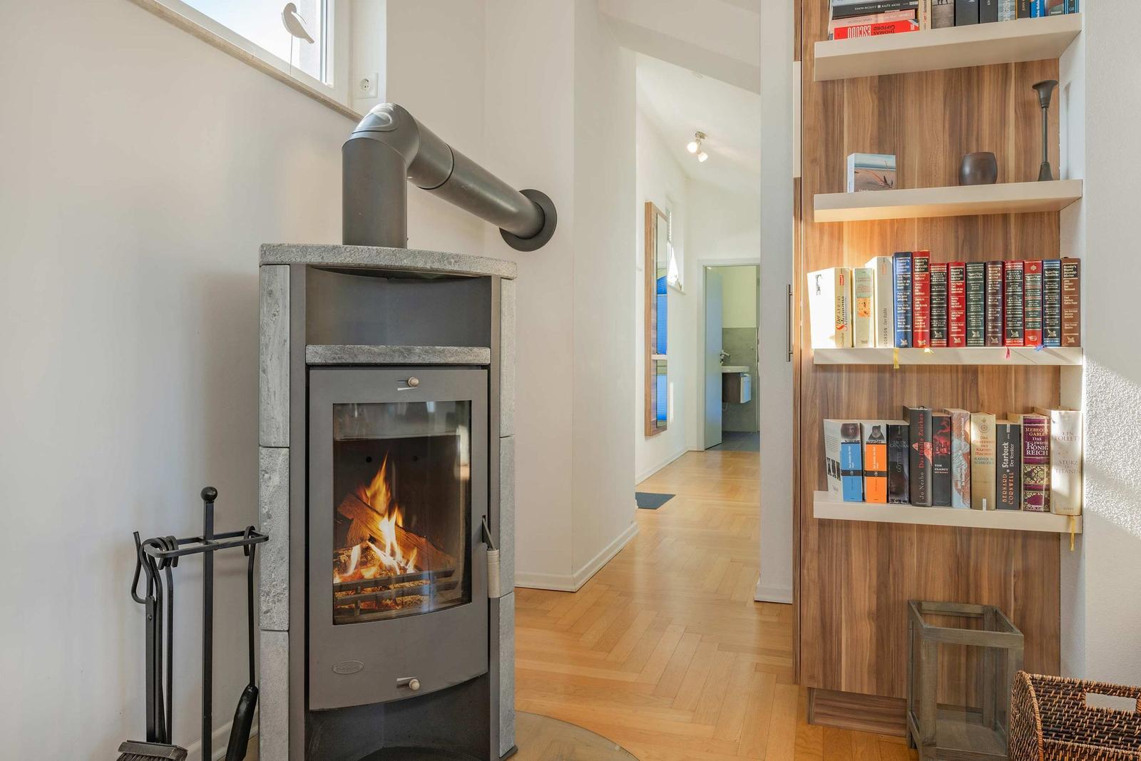 Kaminofen mit brennendem Holz, Bücherregal und Flur mit Holzboden.