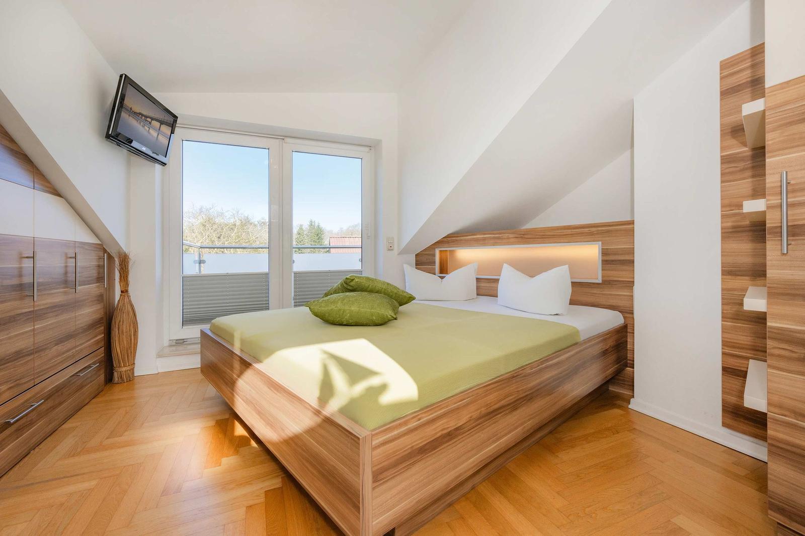 Schlafzimmer mit Doppelbett, Holzmöbel und Balkonansicht