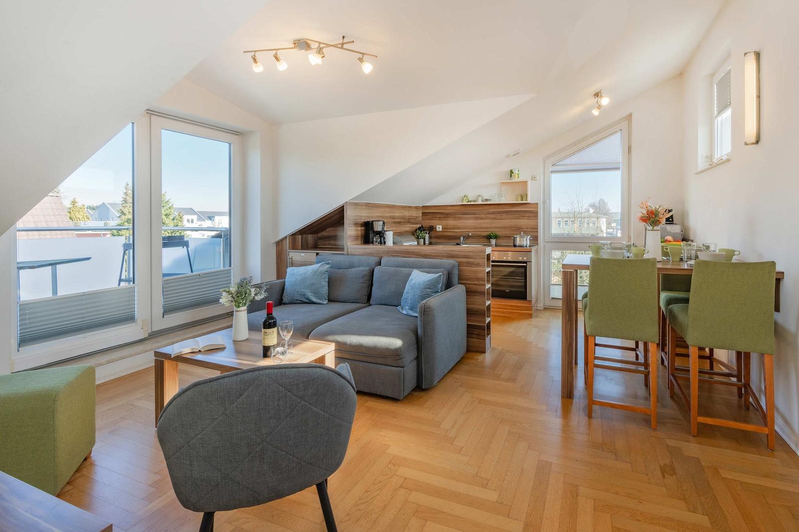 Wohnbereich mit Sofa, Esstisch und Küchenzeile unter Dachschrägen.