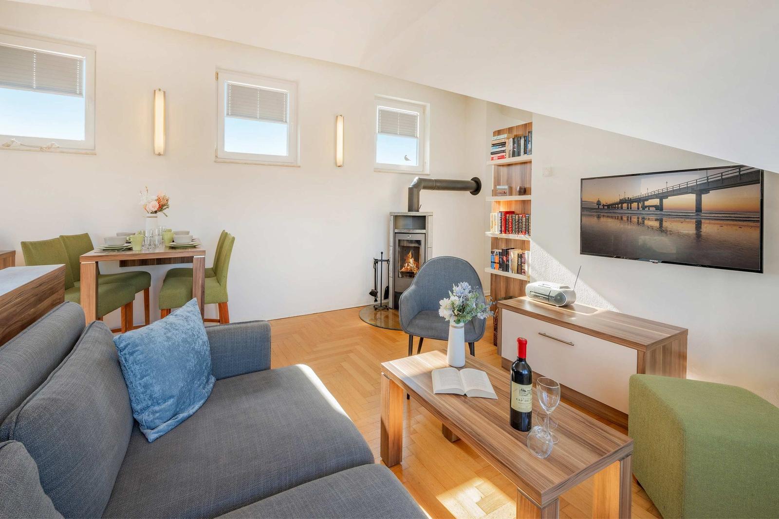 Wohn- und Essbereich mit Kamin, Fernseher und Holzboden.