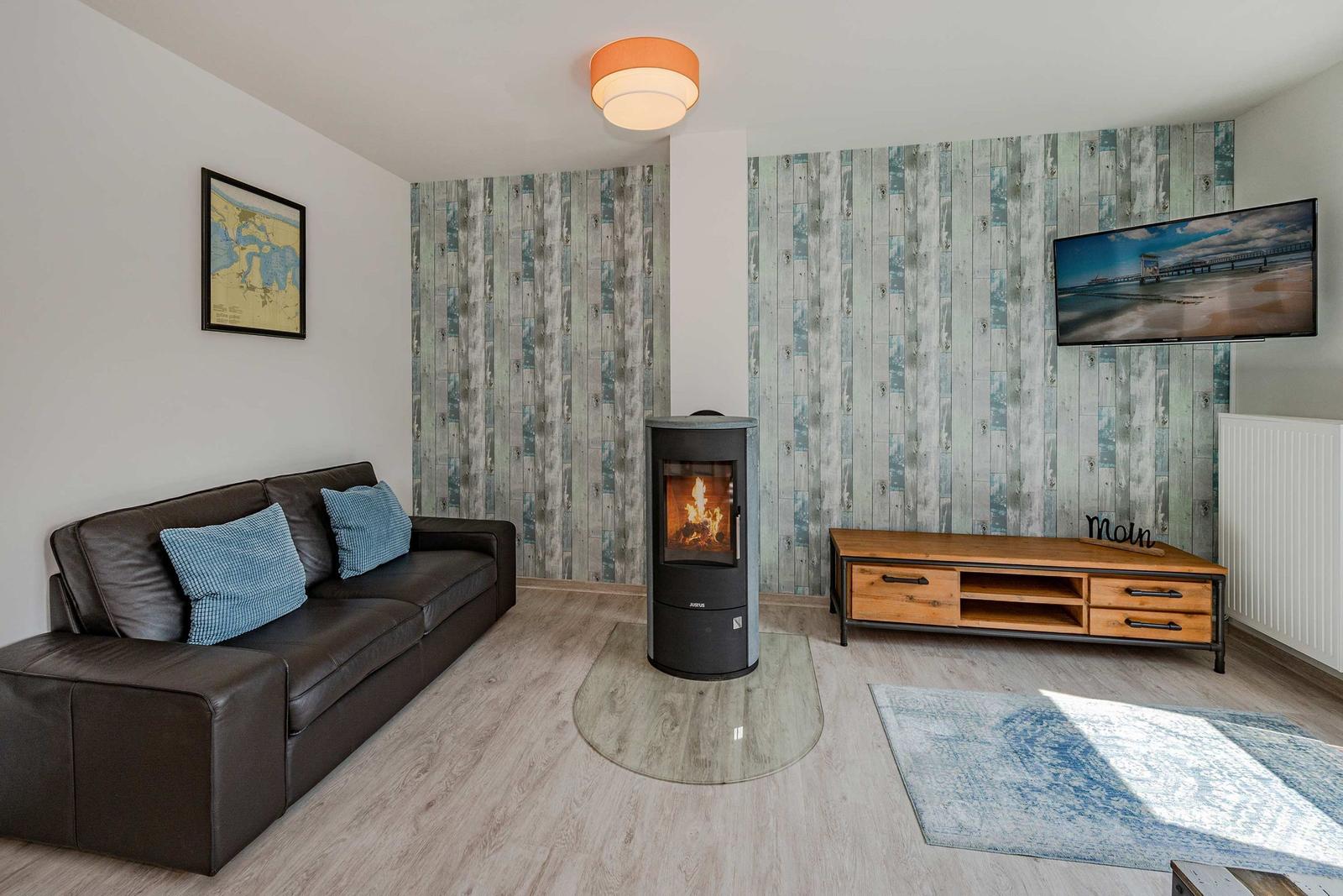 Wohnzimmer mit Sofa, Kamin und Fernseher an Holzwand