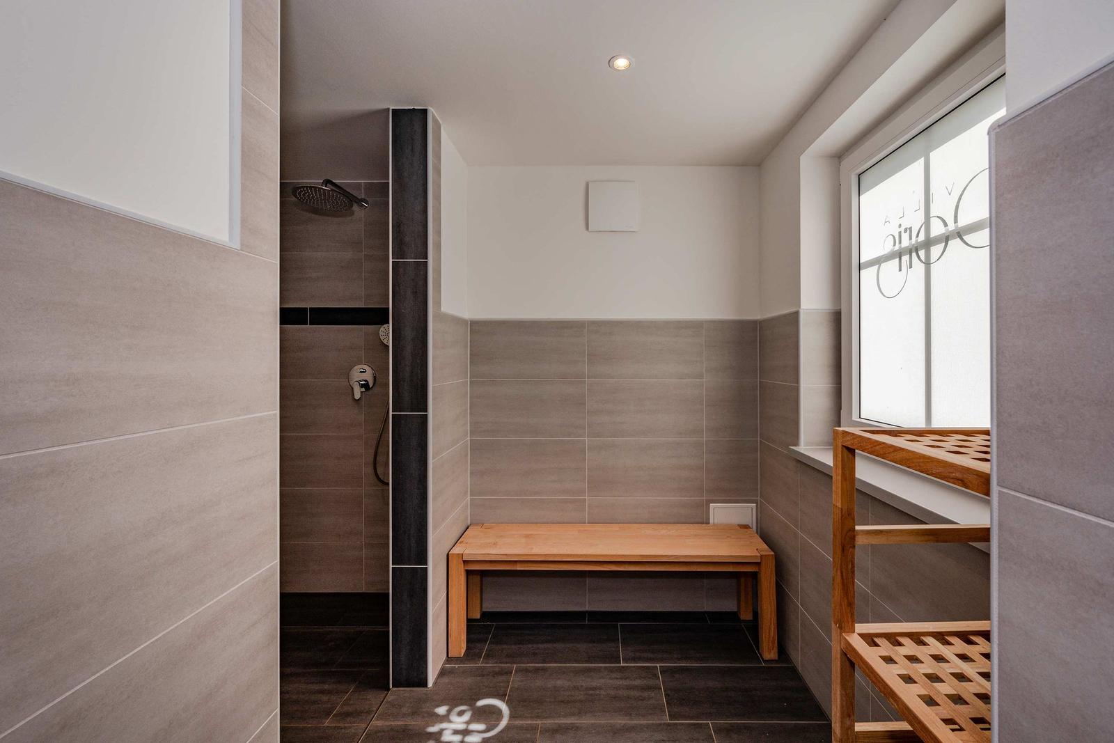 Dusche mit Sitzbank und Holzbank vor Fenster