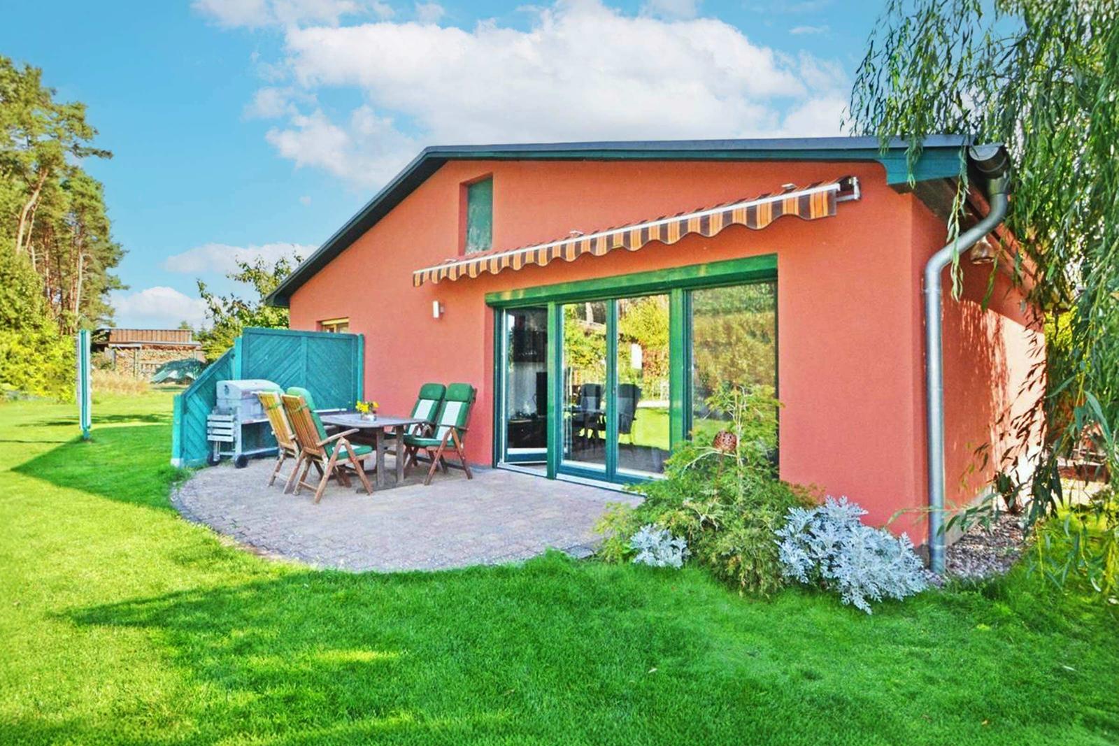 Ein Haus mit Terrasse, Garten und Schiebetüren zur Außenseite.