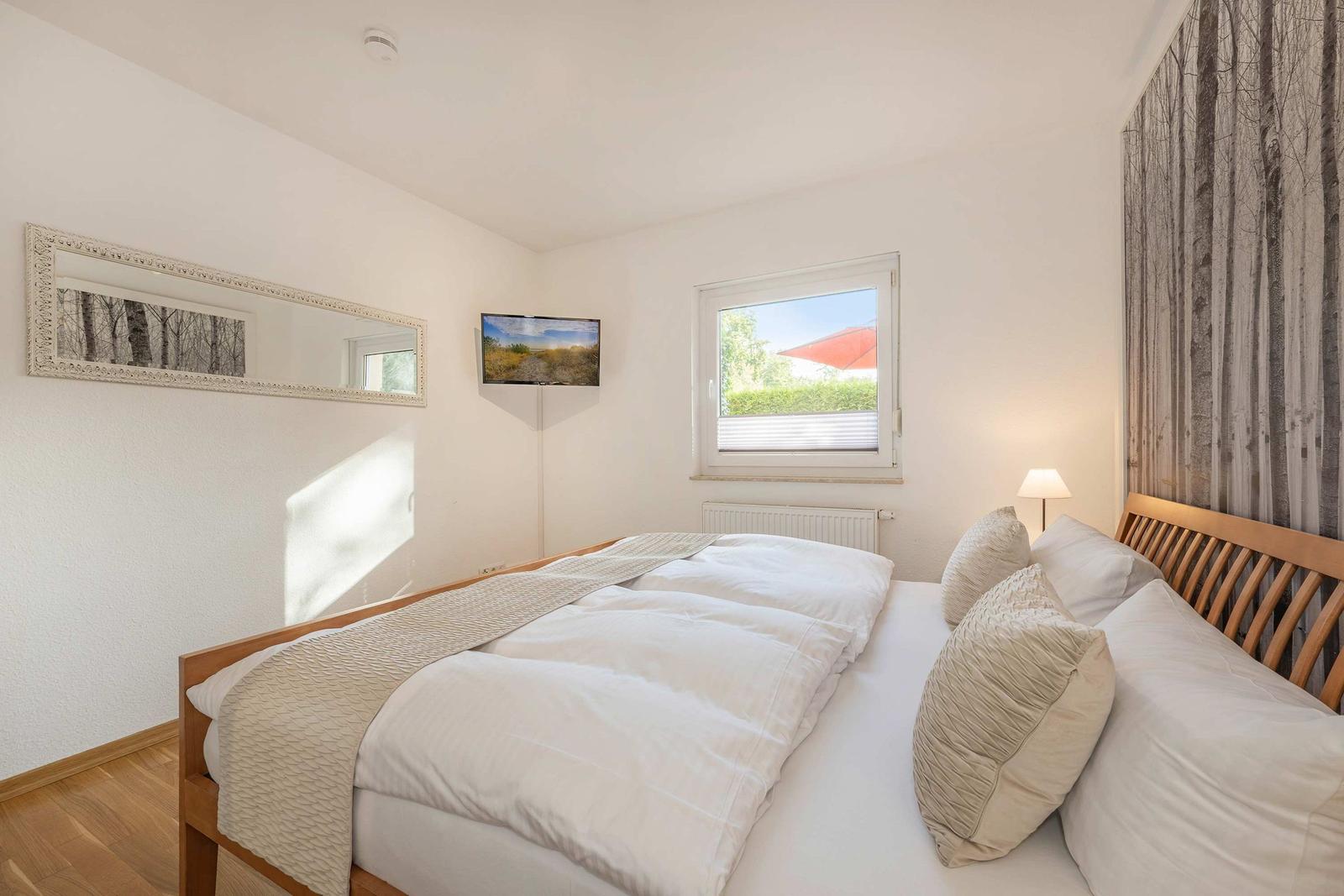 Bedroom with bed, wall art, window, and TV.