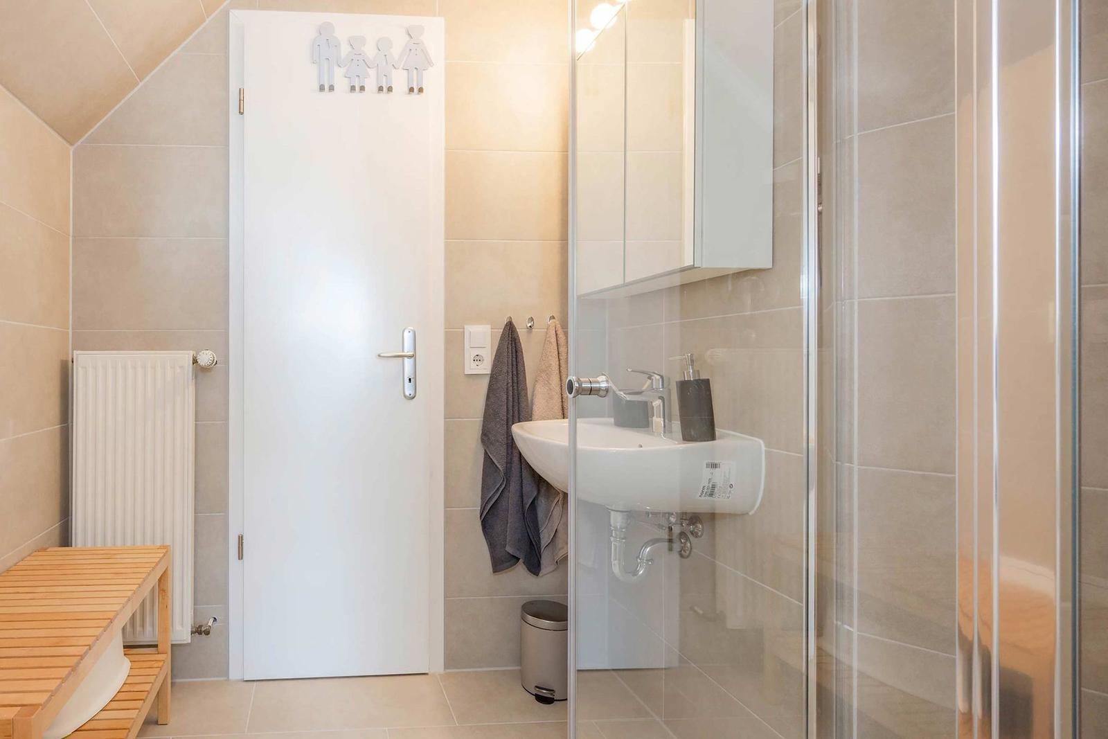 Badezimmer mit Dusche, Waschbecken und Tür mit Familienanhänger.