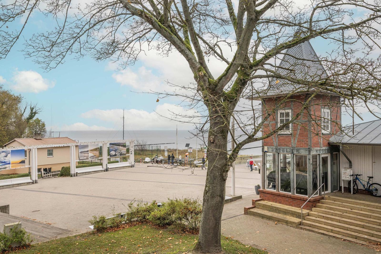 Vorplatz mit Blick aufs Meer, roter Turm und Baum im Vordergrund.