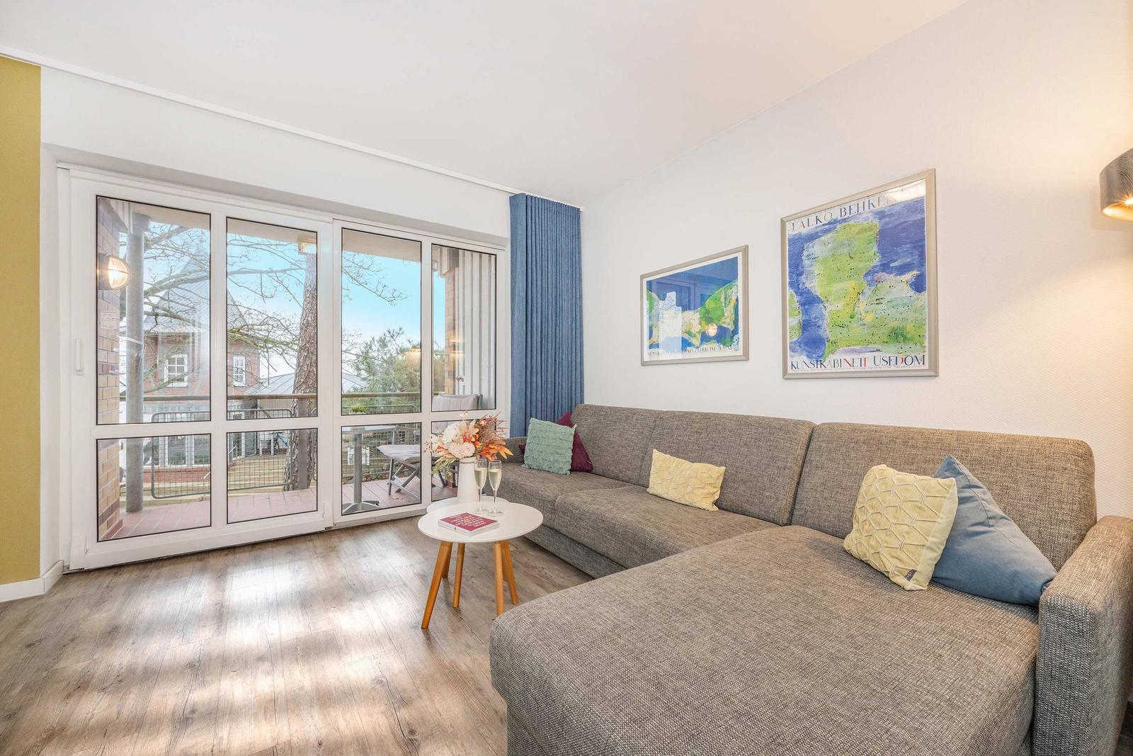 Wohnzimmer mit Sofa, Tisch und Fenster zur Terrasse.