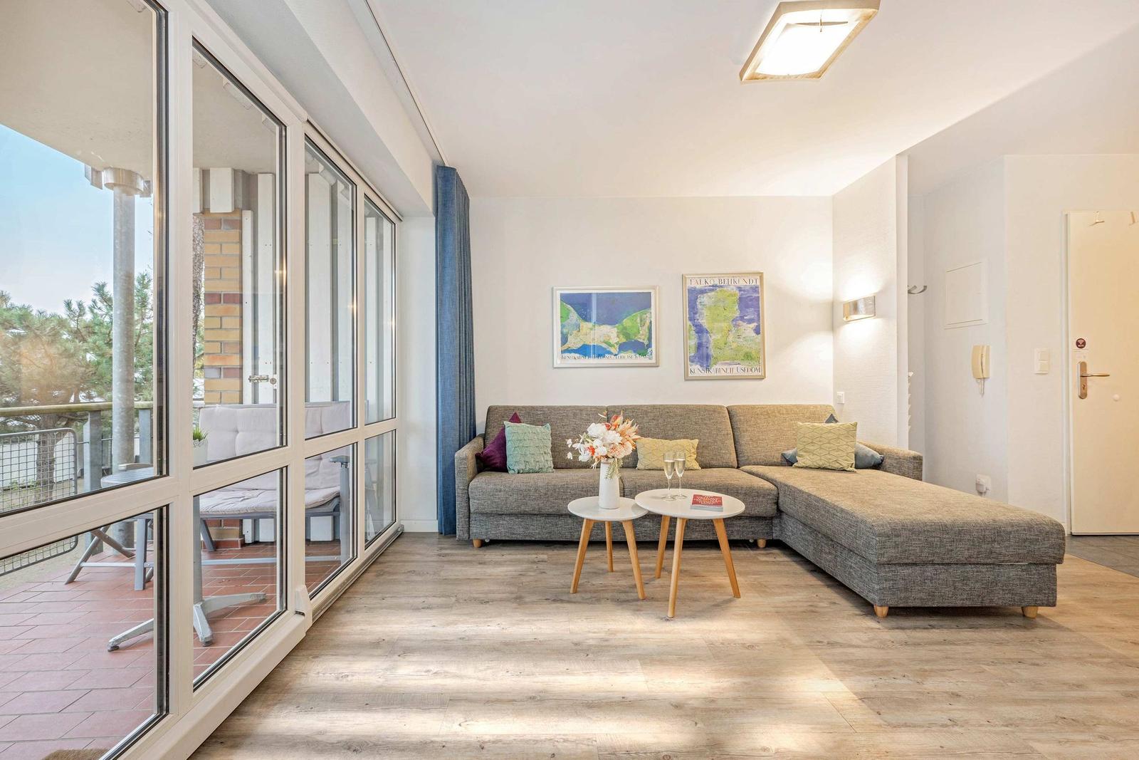 Wohnzimmer mit Sofa, Tisch und Blick auf Balkon.