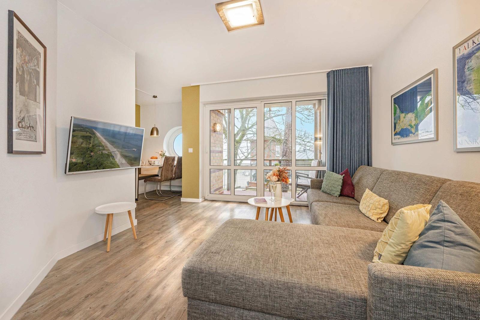 Wohnzimmer mit Sofa, Fernseher und Glastür zur Terrasse