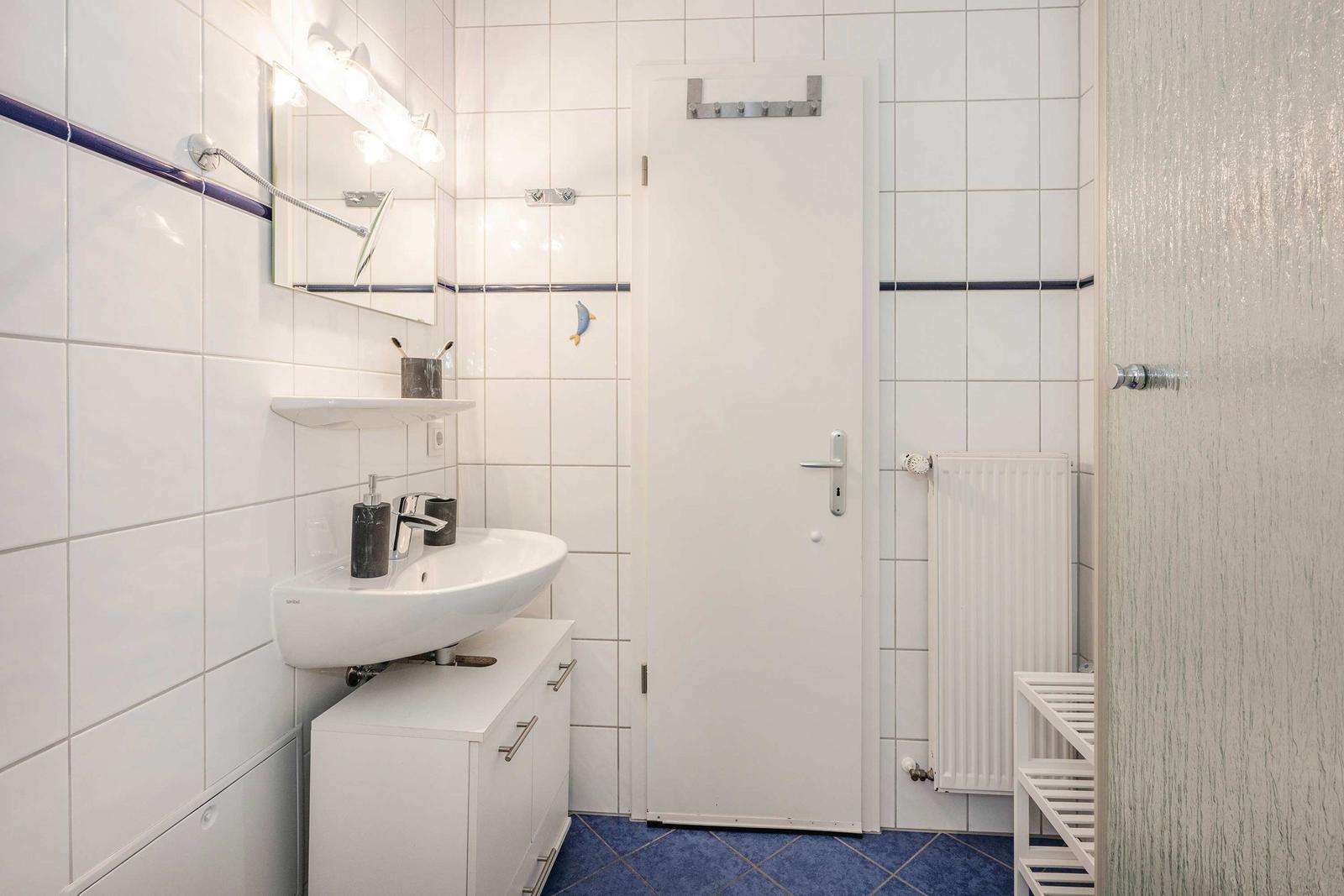 Badezimmer mit Waschbecken, Spiegel und Heizkörper an der Wand.